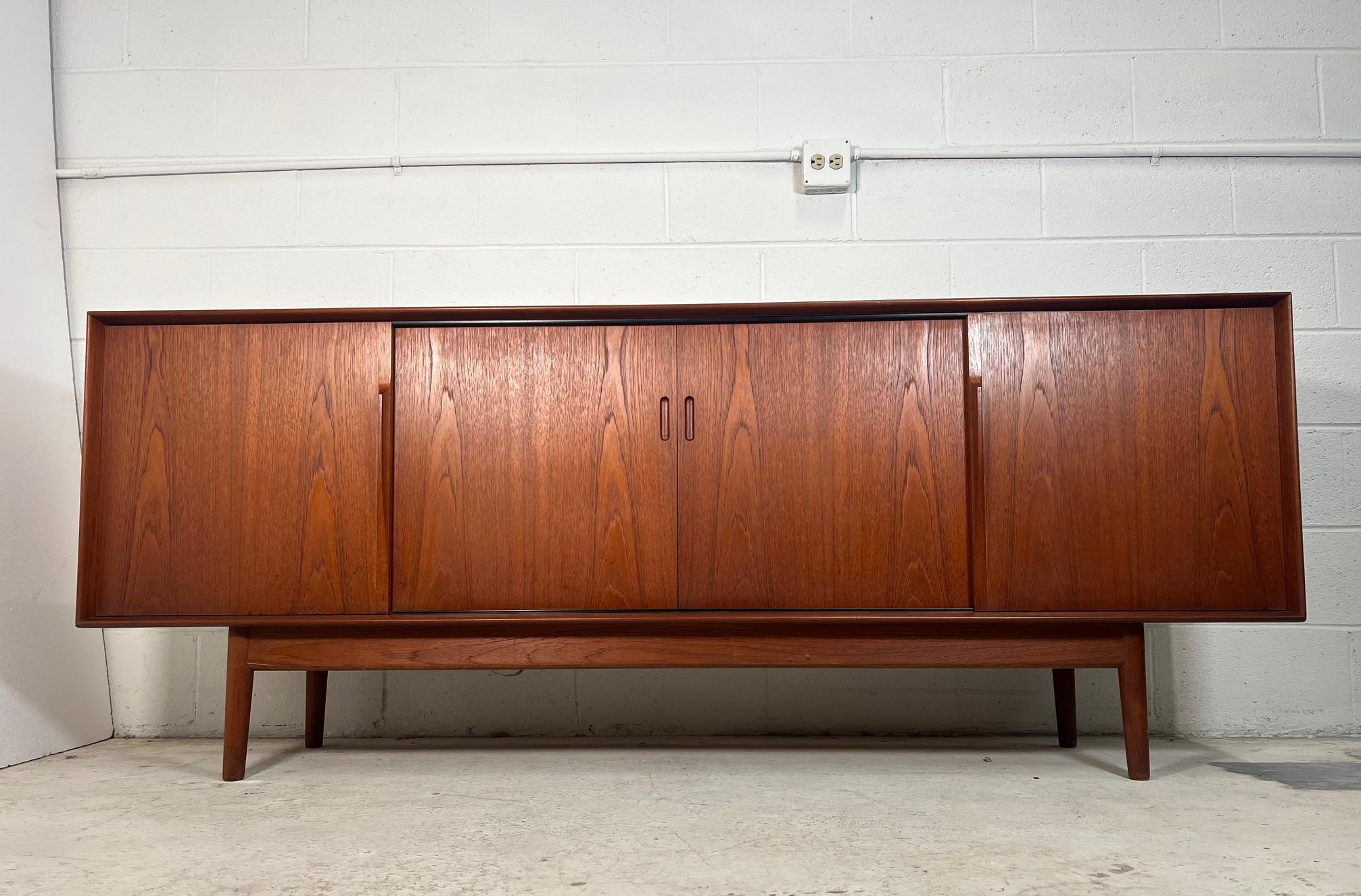 Outstanding teak credenza or buffet. Made in England by Dalescraft. Featuring two sets of sliding doors. Three drawers on the left side. Removable shelves in the middle. Shelf on the right is missing. Finished back. Minor signs of wear. Some marks