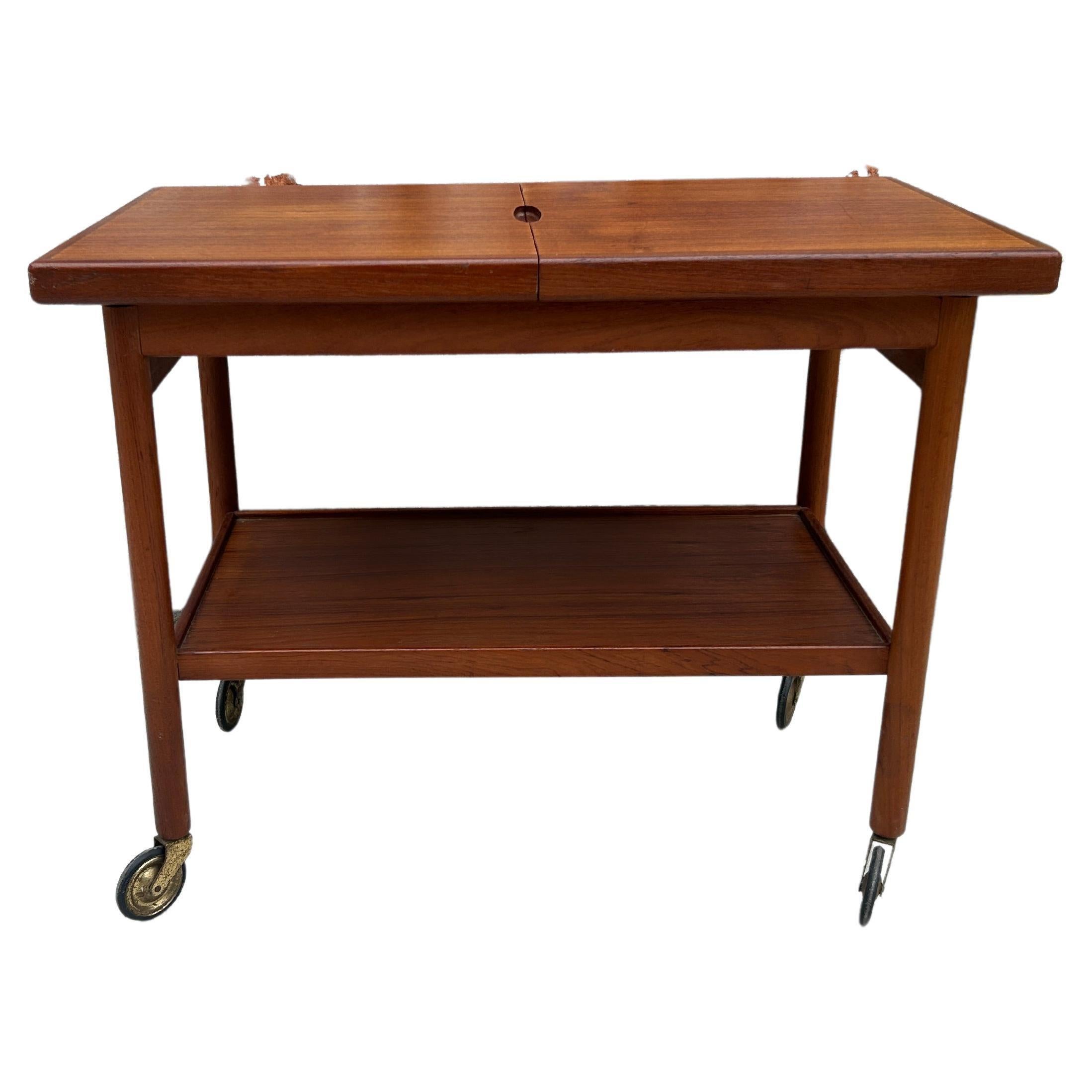 Simple mid century Danish modern teak bar cart server with two drawers and a lower shelf on casters. Solid teak wood construction top extends to reveal a black laminate center top. Original vintage condition clean all around. Burn label under lower