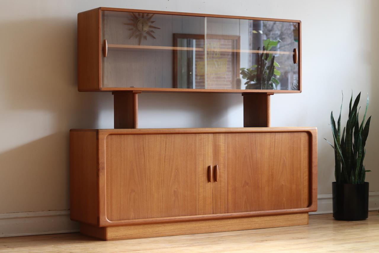 Scandinavian Mid-Century Modern teakwood sideboard.
Floating glass display case.
Tambour door credenza.
Adjustable shelving in top and bottom.
Two piece unit.
Five dovetailed drawers in the center.

Overall: 75