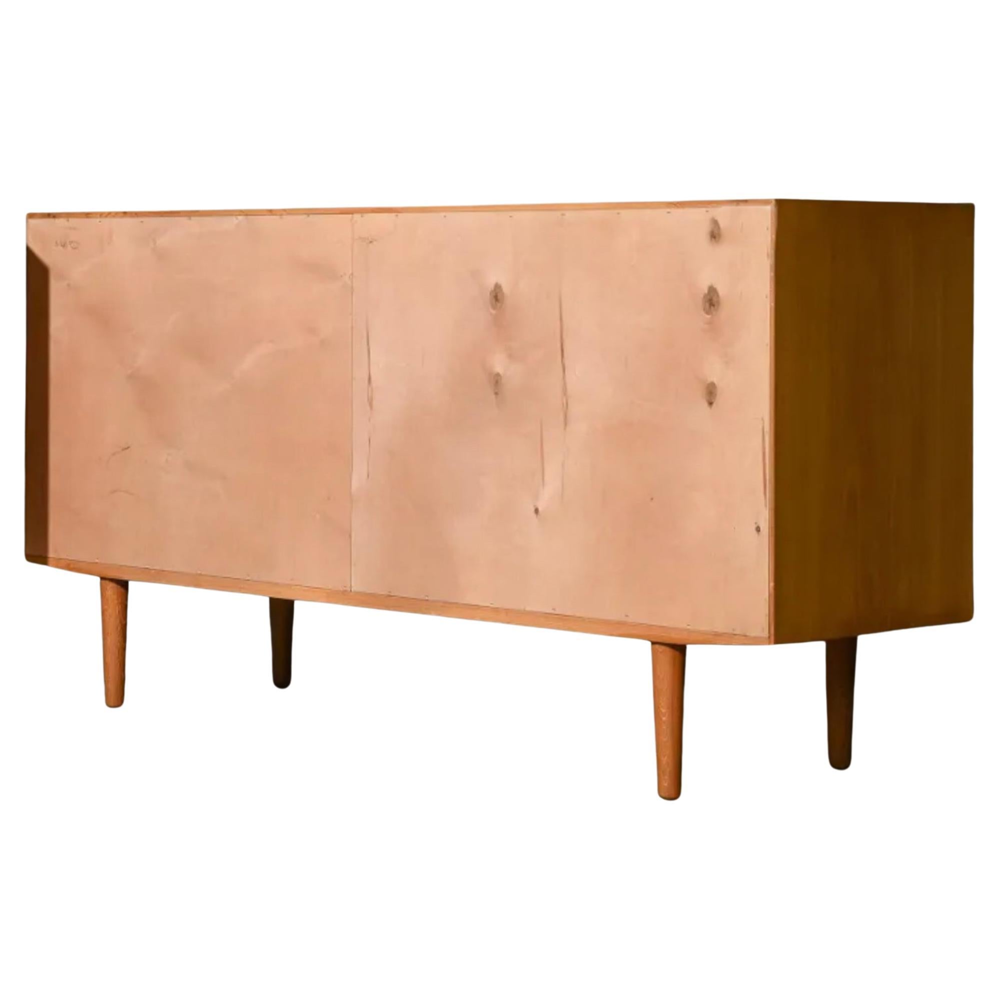 Midcentury Danish modern teak sliding door credenza. Has 2 front sliding doors with rounded carved teak handles. Has 2 adjustable shelves w/pins in each section. Labeled Danish Control inside. Good excellent condition inside and out. Sits on 4 solid