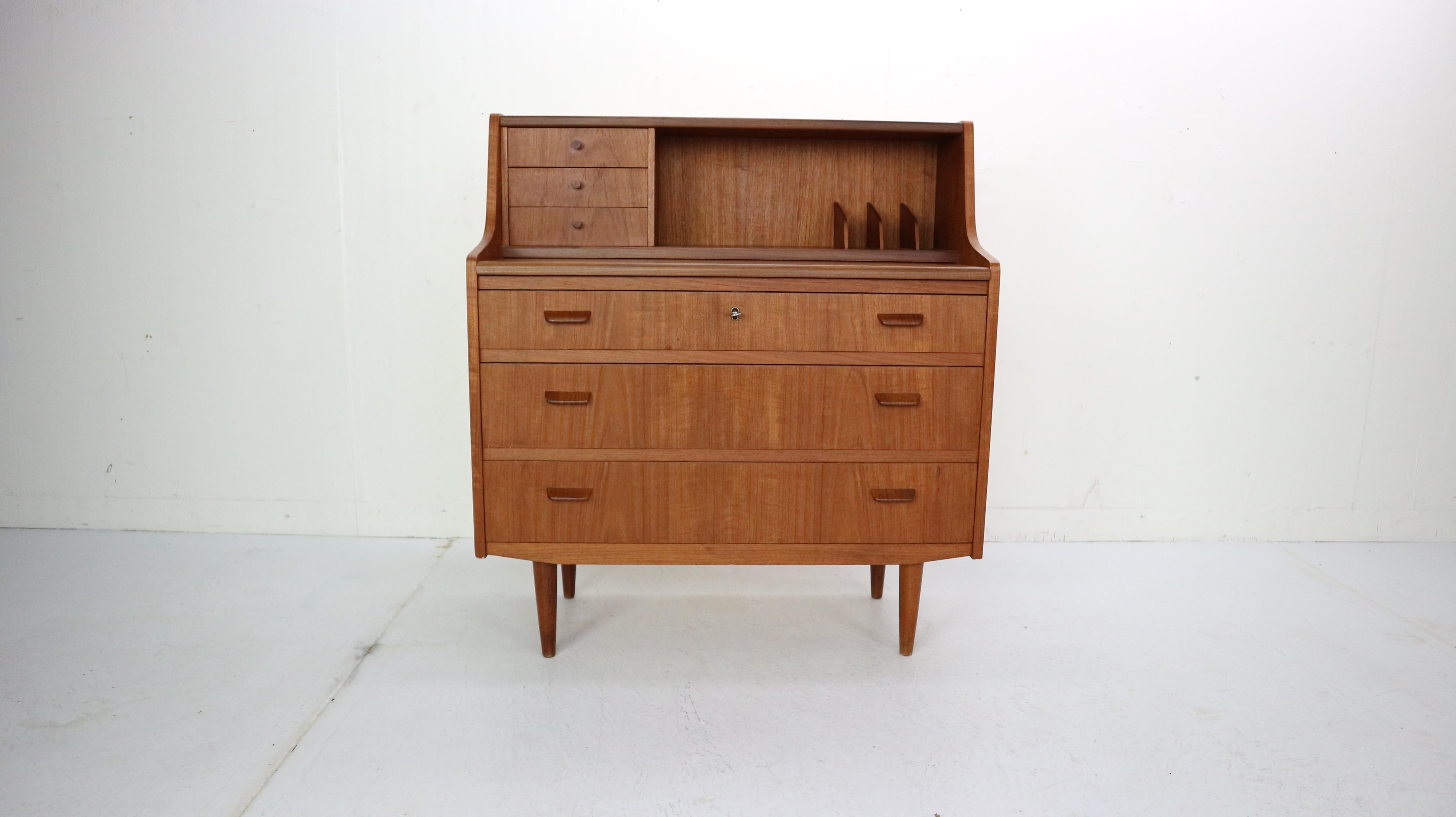 This midcentury Danish modern teak secretary desk was made in Denmark, circa 1960. The Classic Scandinavian Modern design has clean Minimalist lines and elegant curves. The upper cabinet features three small top drawers, storage space and a pull-out