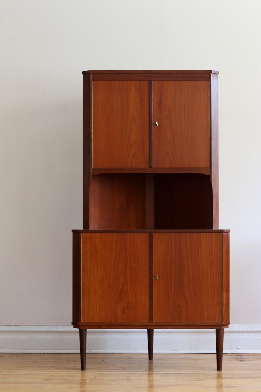 Danish Mid-Century Modern locking teak corner cabinet.
Just imported from Denmark!
Two locking cabinet doors with shelving.
Comes with vintage key which locks each compartment.
Beautiful teak woodgrain.
Excellent vintage condition!
Measures: