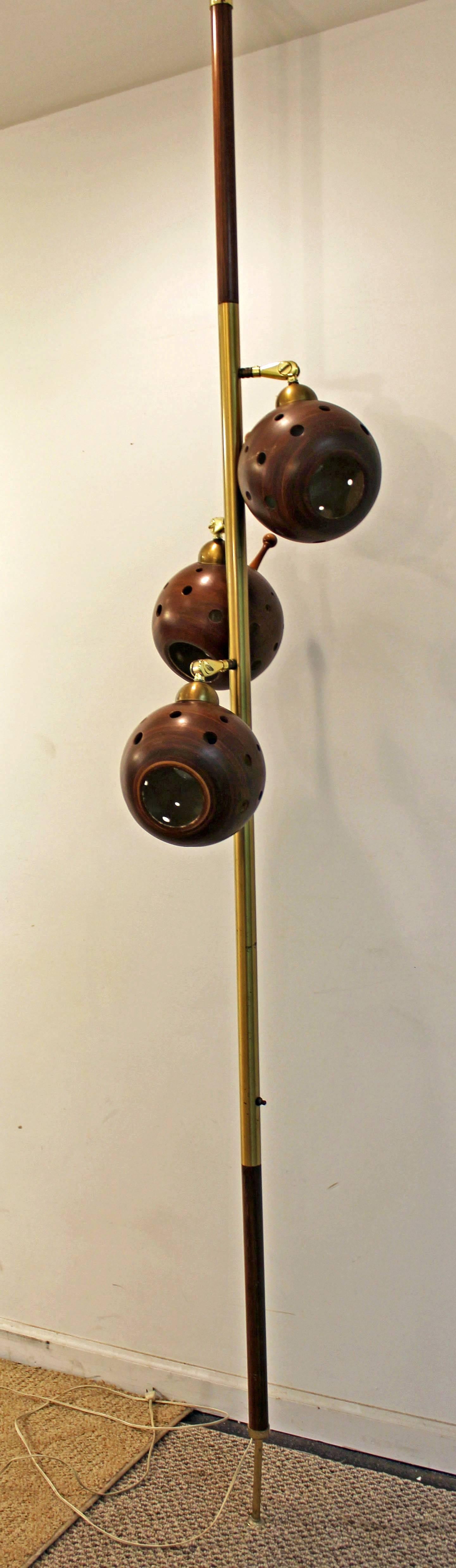 Offered is a retro Mid-Century Modern tension pole lamp. This is an adjustable three-way lamp, featuring three pivoting faux walnut shades and brass handles. Has been tested and is in good, working condition.

Dimensions:
18