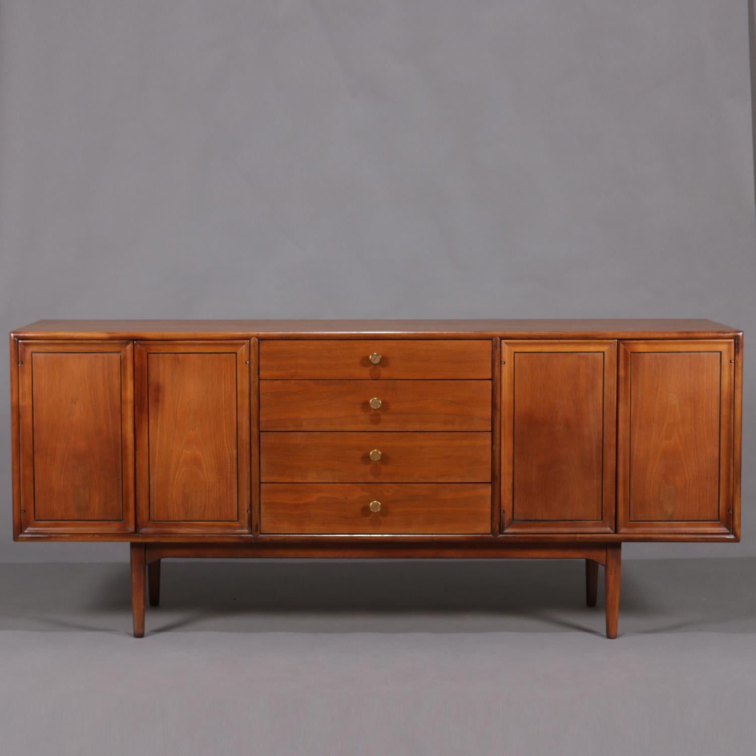 Midcentury Danish modern declaration credenza by Drexel features designing by by Kipp Stewart and Stewart McDougall and includes walnut construction having four stacked central drawers flanked by cabinets each having adjustable shelving, one with