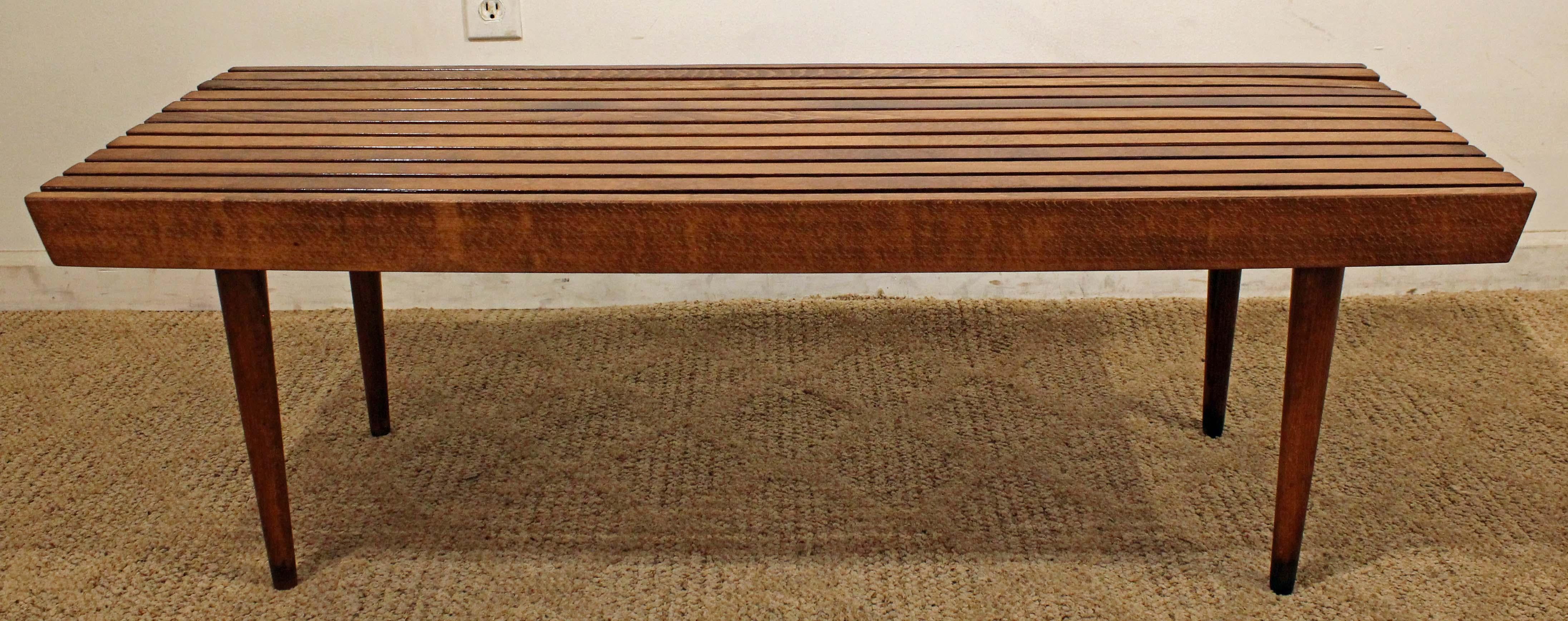 What a find. Offered is a midcentury coffee table. Features a slat bench top on pencil legs, made of walnut. The piece is in good condition, shows minor age wear. It is not signed.

Dimensions: 
48