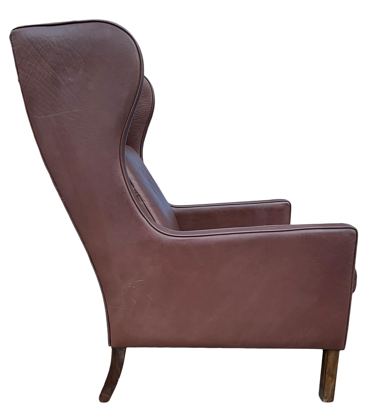 Mid century Danish modern wingback reddish Brown leather fireside chair in the by Børge Mogensen with beautiful patina. Chair shows wear and use. All original vintage used patina. Beautiful Dark reddish Brown leather. Solid teak legs. Made In