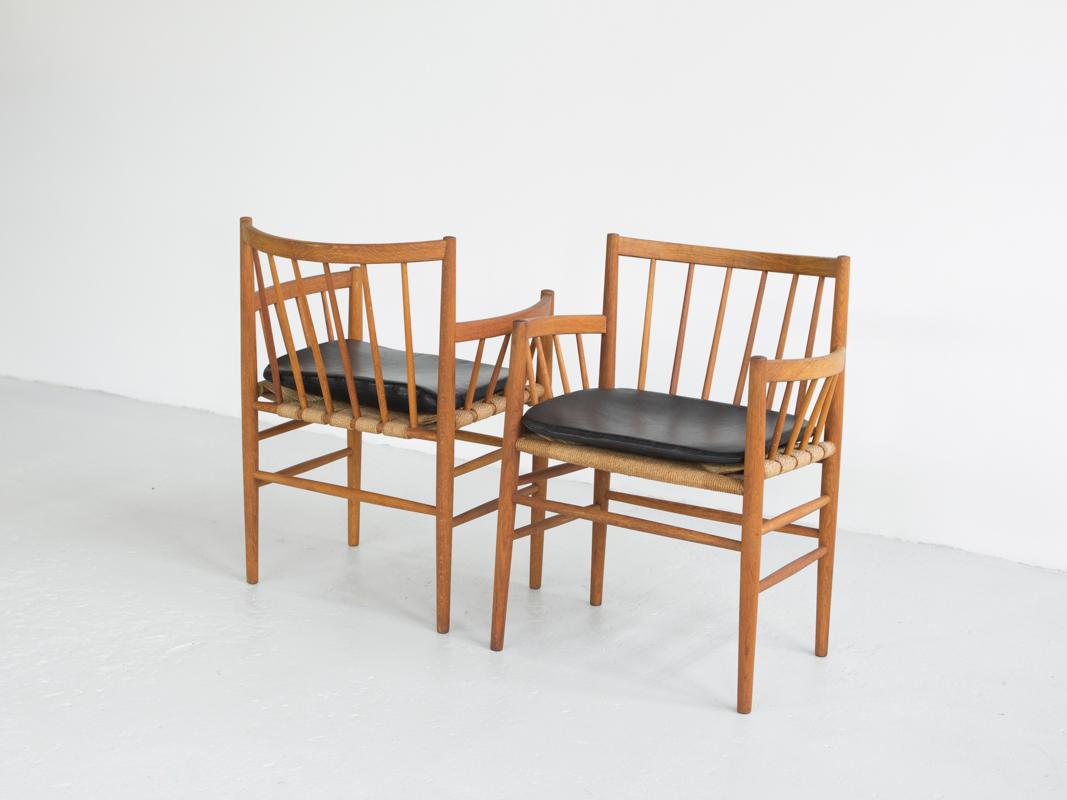 Midcentury pair of chairs designed by Jørgen Baekmark and manufactured by FDB in Denmark in the 1960s. Model: J81. The chairs have beautiful rounded arm rests. They are in solid oak and have the original Danish paper cord seat. The fitting leather
