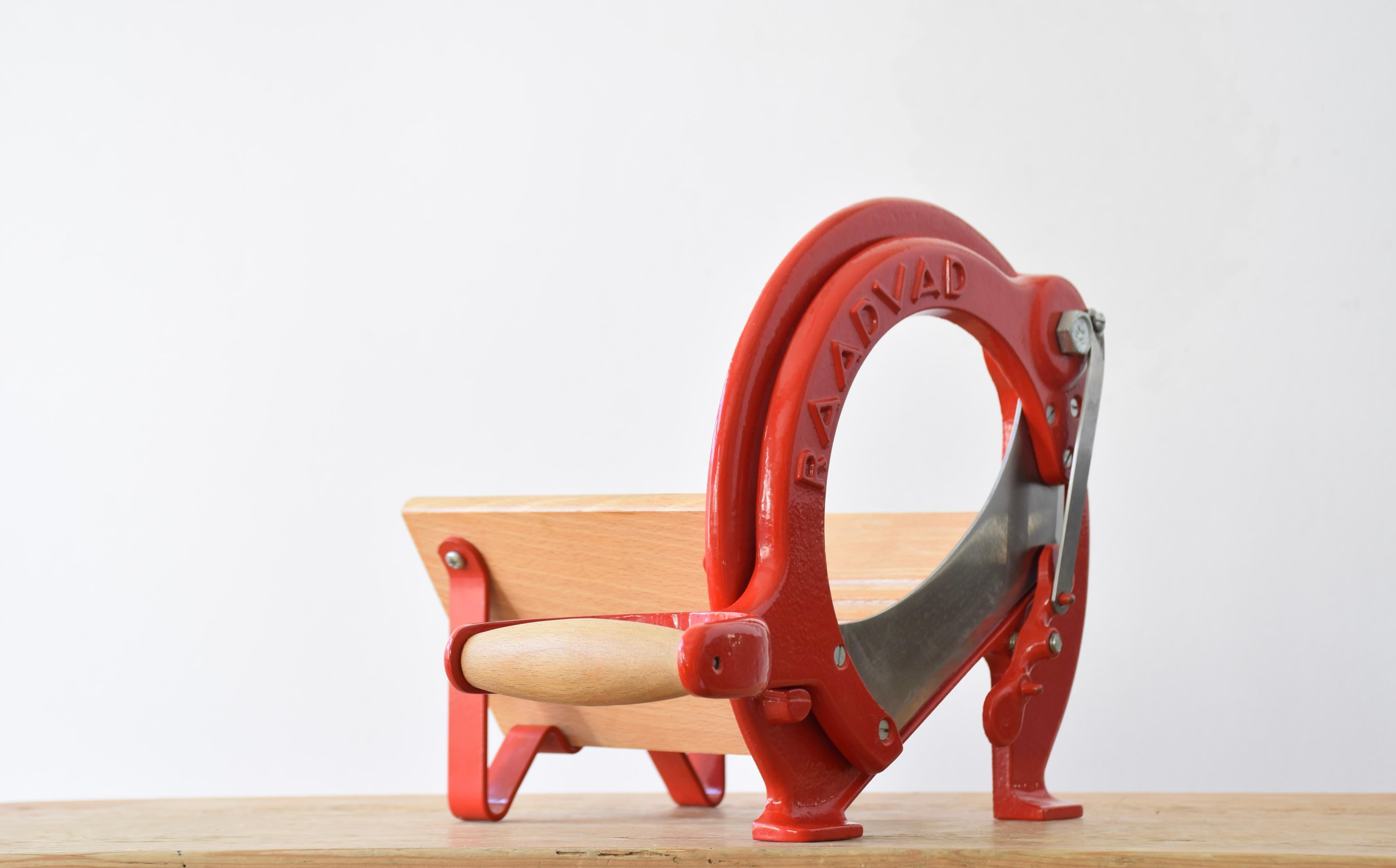 This iconic Danish bread slicer was produced by Raadvad in Denmark, circa 1970s-1980s. It comes with the original red lacquer. The red version is more rare to find. The bread slicer is fully functional for slicing bread, especially black bread and