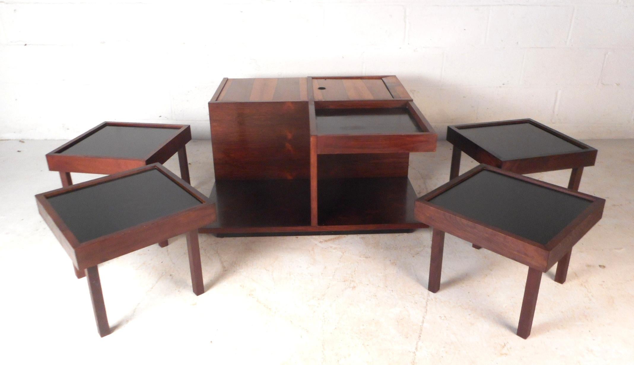 This extremely unique vintage modern coffee table features a storage compartment on top with a lock, a lazy Susan, and four additional smaller tables. The versatile design functions as a table with storage or a bar. Four additional tables are