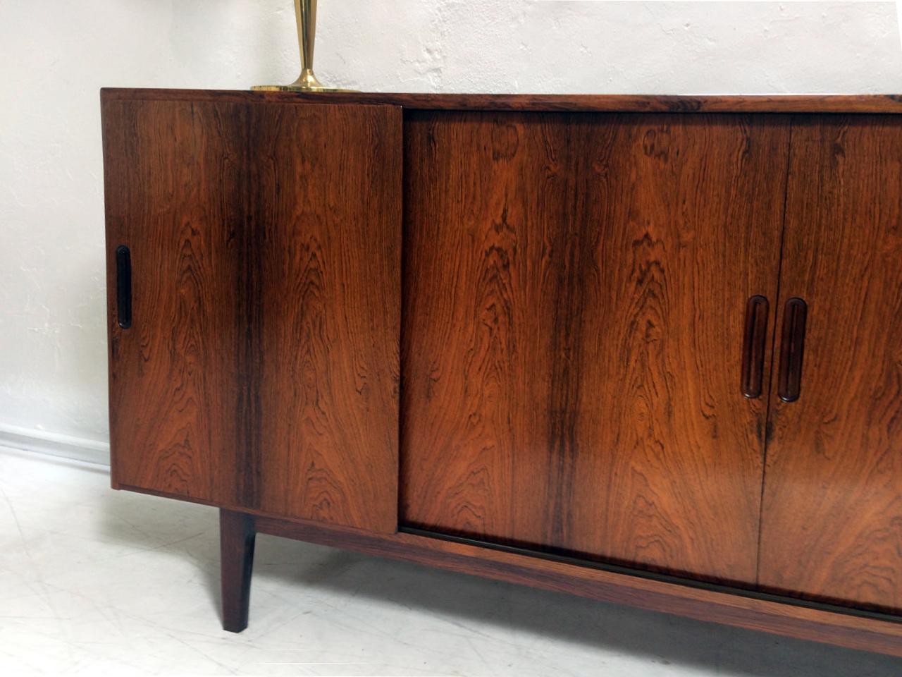 A superb Danish rosewood highboard in the style of Gunni Omann. The left hand door slides to reveal five green baise lined drawers, the central and right hand compartment contain adjustable shelves.
Super build quality, lovely veneers and in