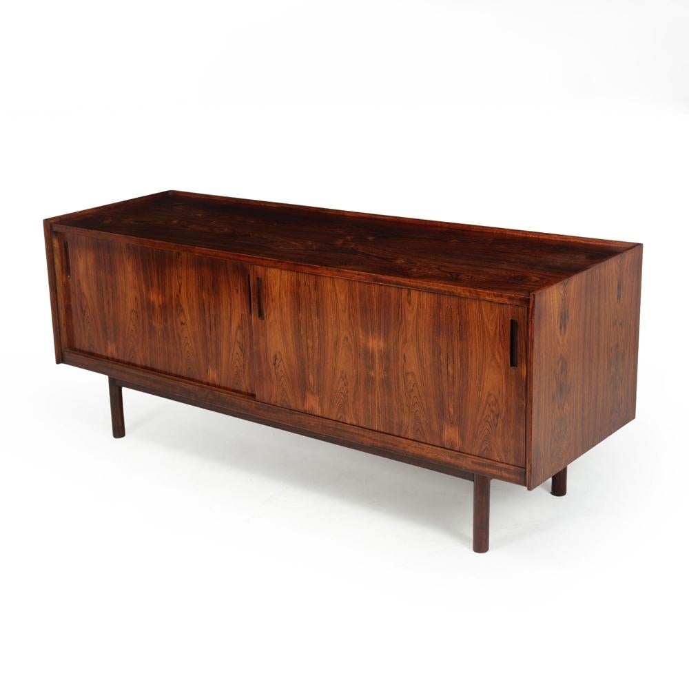 A small Danish sideboard designed by Kofod Larsen with two sliding doors and finger jointed drawers behind, free-standing it can be used as a room divider and it has a lipped top and turned legs. The sideboard is of great quality and has been fully