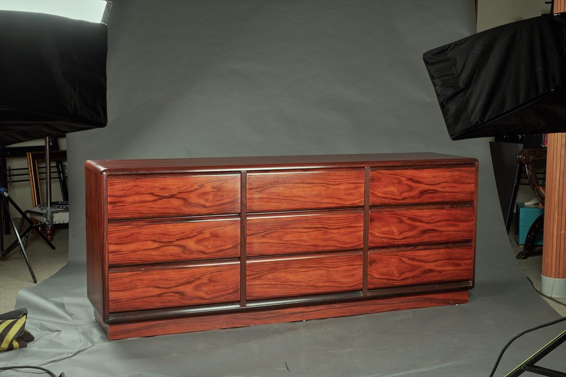 Sideboard has nine spacious drawers with no handle and its top displays beautiful rosewood grain. Rests on a solid rectangular wooden base.
Brauer Manufacture
Danish, circa 1950s.
Measures: 75” x 18” x 30”.
Provenance: From the estate of the