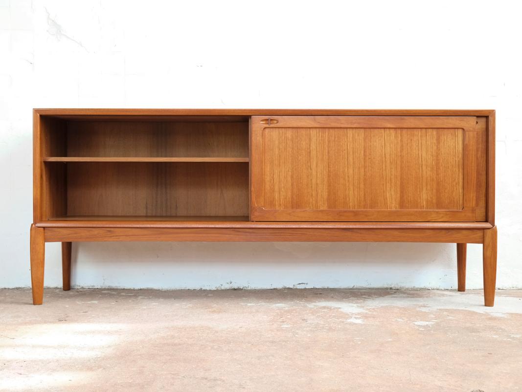 Midcentury sideboard designed by HW Klein and manufactured by Bramin in Denmark in the 1960s. The sideboard has a specific design of the front legs and door handles. The legs are at the corners of the sideboard. The long doors are functioning very