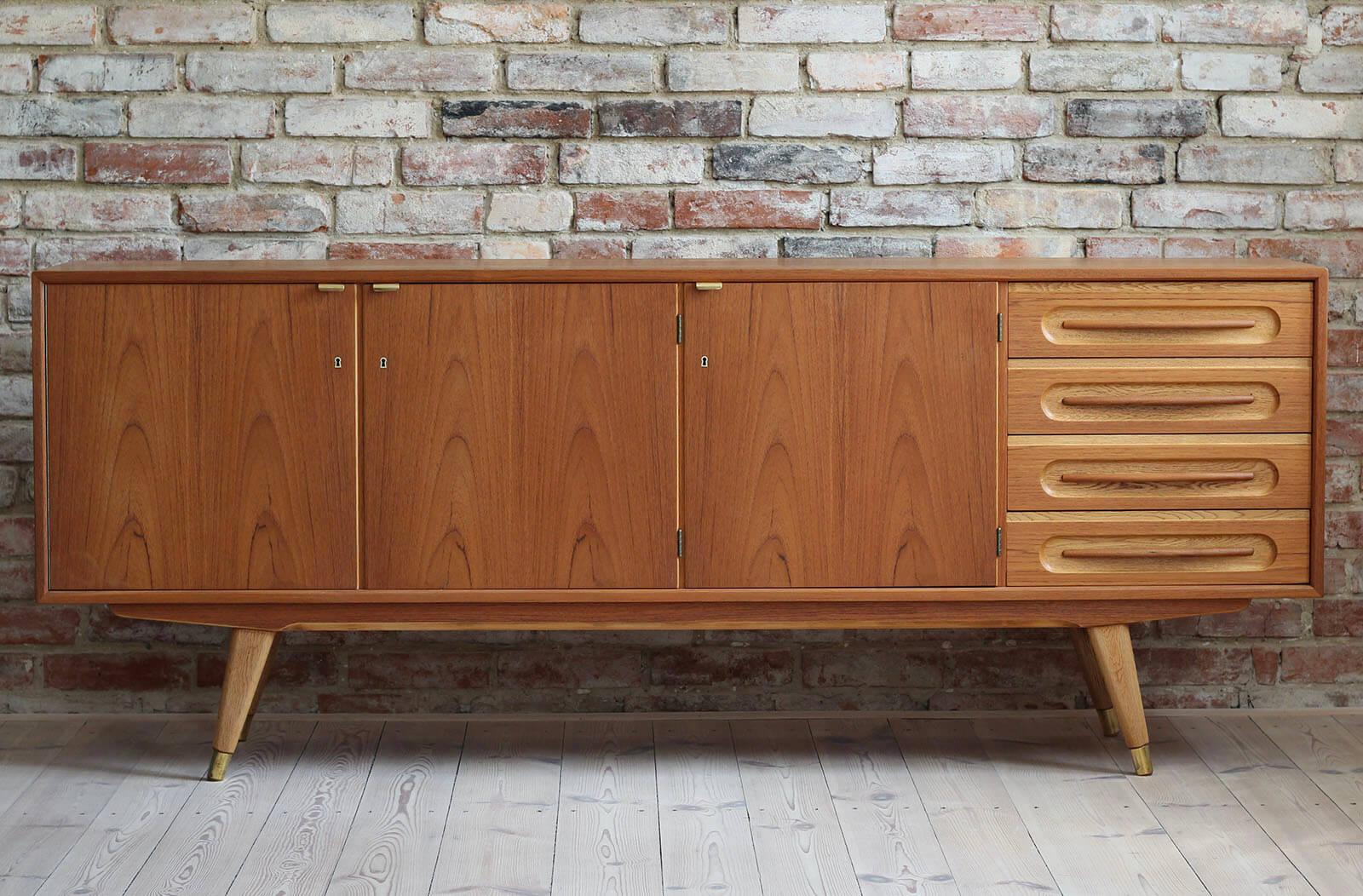 This teak sideboard comes from Denmark and was made around 1960s. It features four storage sections, three of them shelves, each one lockable with a key. The right section features four spacious drawers. Each drawer has beautifully sculpted handle.