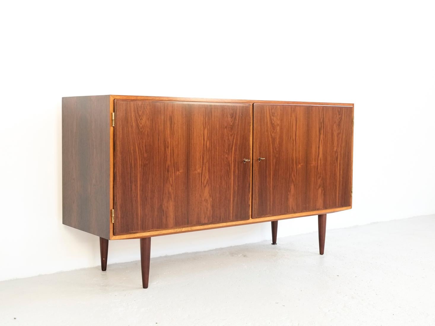 This midcentury sideboard is designed and manufactured by Hundevad in Denmark in the 1960s. True high quality manufacturing in rosewood. Beautiful veneer selection. 2 original brass color keys available. The sideboard is stamped by the manufacturer