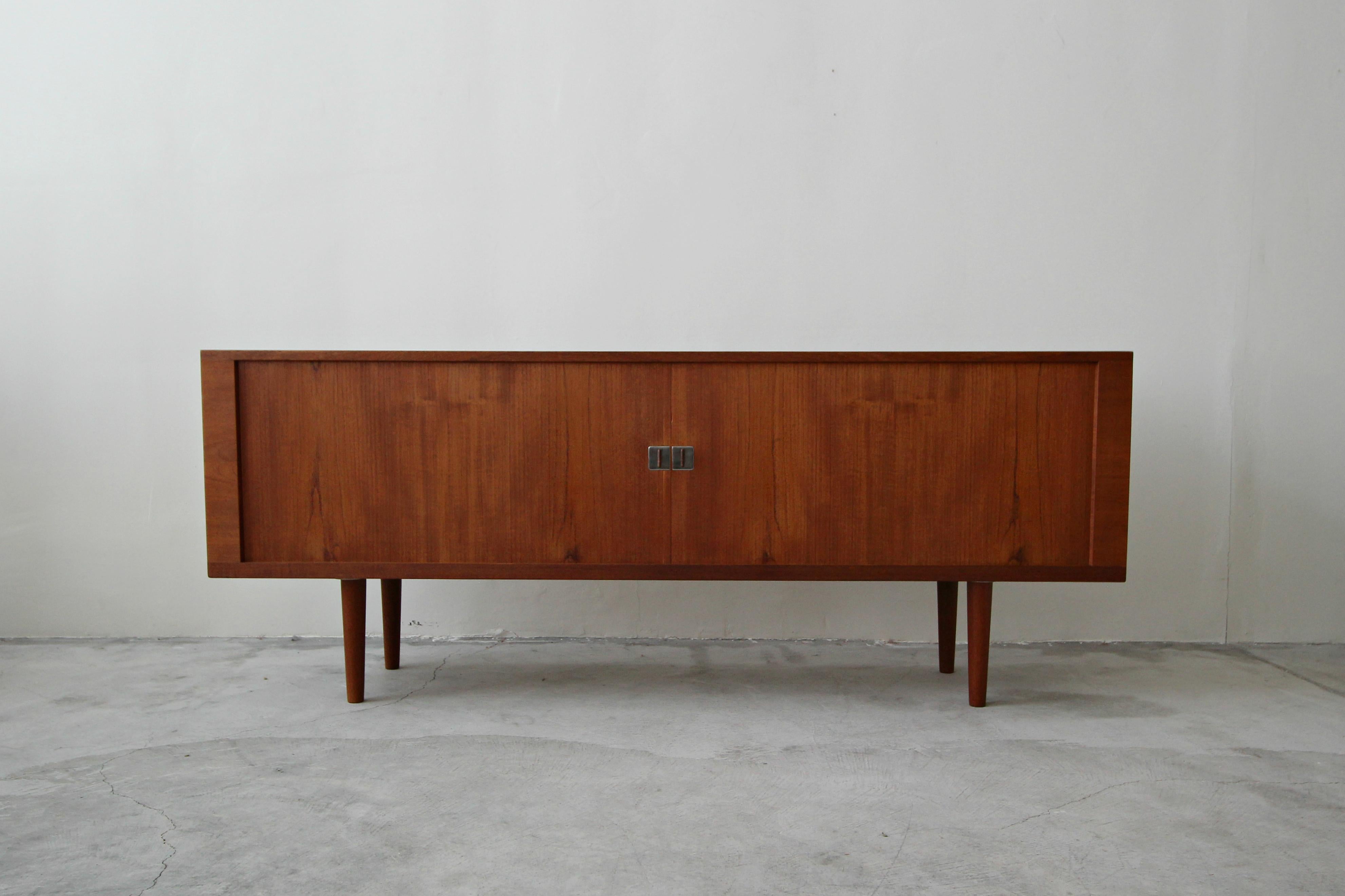 The president credenza by Hans Wegner for Ry Mobler is a Danish classic. Features beautiful teak graining, unique teak and chrome pulls and sliding tambour doors. Behind the tambours are 3 compartments, 2 with 2 shelves each and a centre section