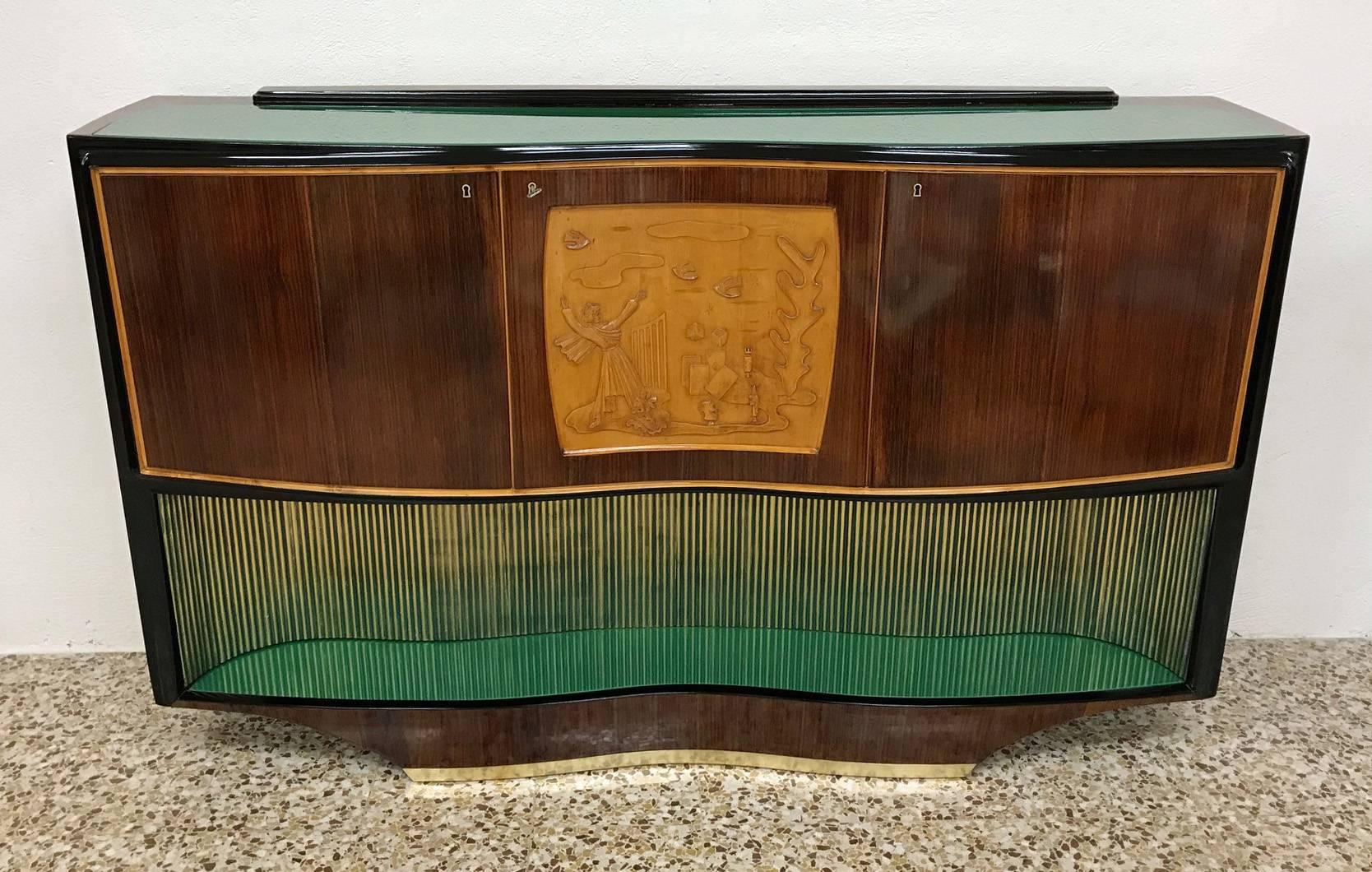 This buffet was produced in Italy in the 1950s by Vittorio Dassi for ' Esposizione Permanente mobili Cantù '.
The central doors are embellished by a fine maple carving, the solid wood base is green lacquered with gold details. The top is covered