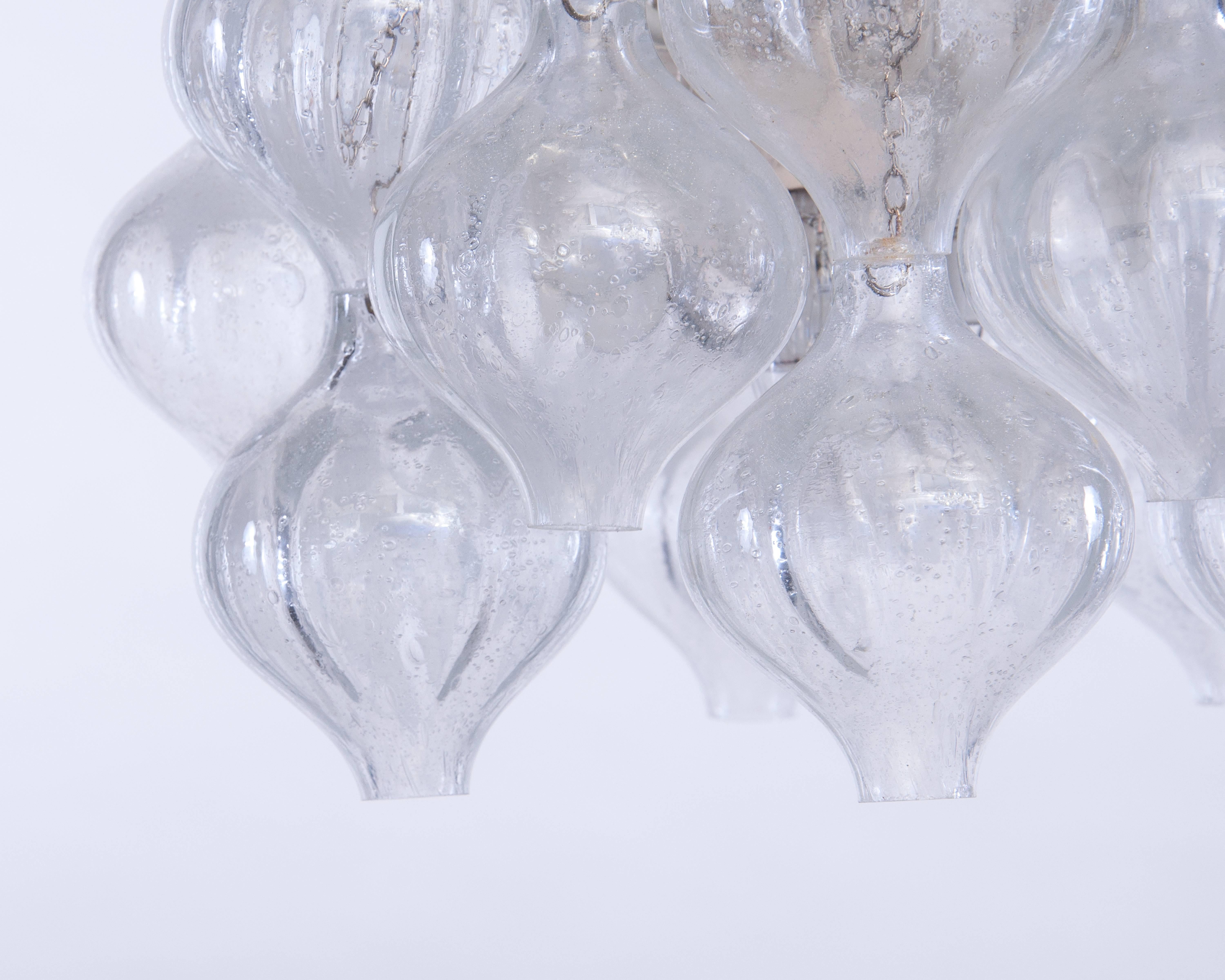 A beautiful midcentury chandelier by the famous designer J.T. Kalmar called Tulipan.
The chandelier consists of a white metal structure and has 12 arms, each arm has two handblown onion-shaped glass spheres.
The spheres are attached to the frame