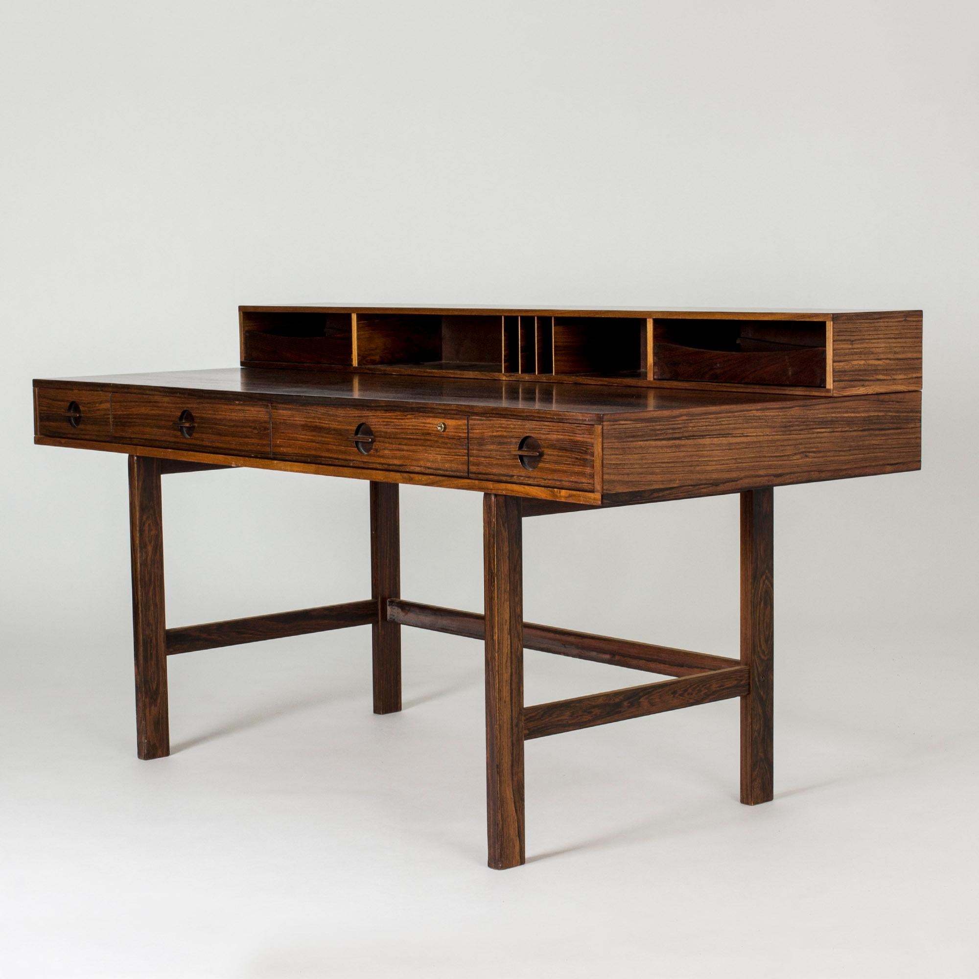 Amazing, versatile desk by Peter Løvig Nielsen, made in beautiful rosewood. The shelf on the table top can be flipped to extend the depth of the desk. Shelves on both sides, possible to be used by two people at the same time. Nice attention to