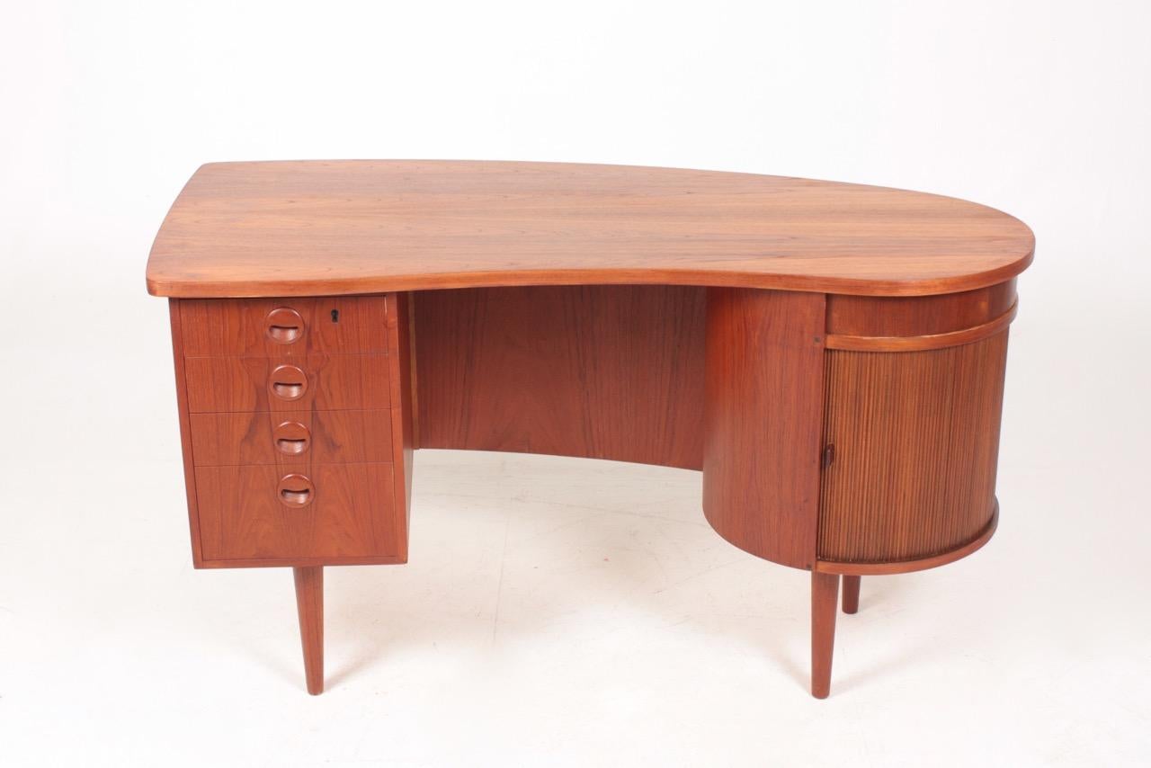 Great looking freestanding desk in teak with a bank of four drawers and a roll front dry bar section. Designed by Kai Kristiansen M.A.A. for FM Furniture, Denmark in 1950s. Original condition.