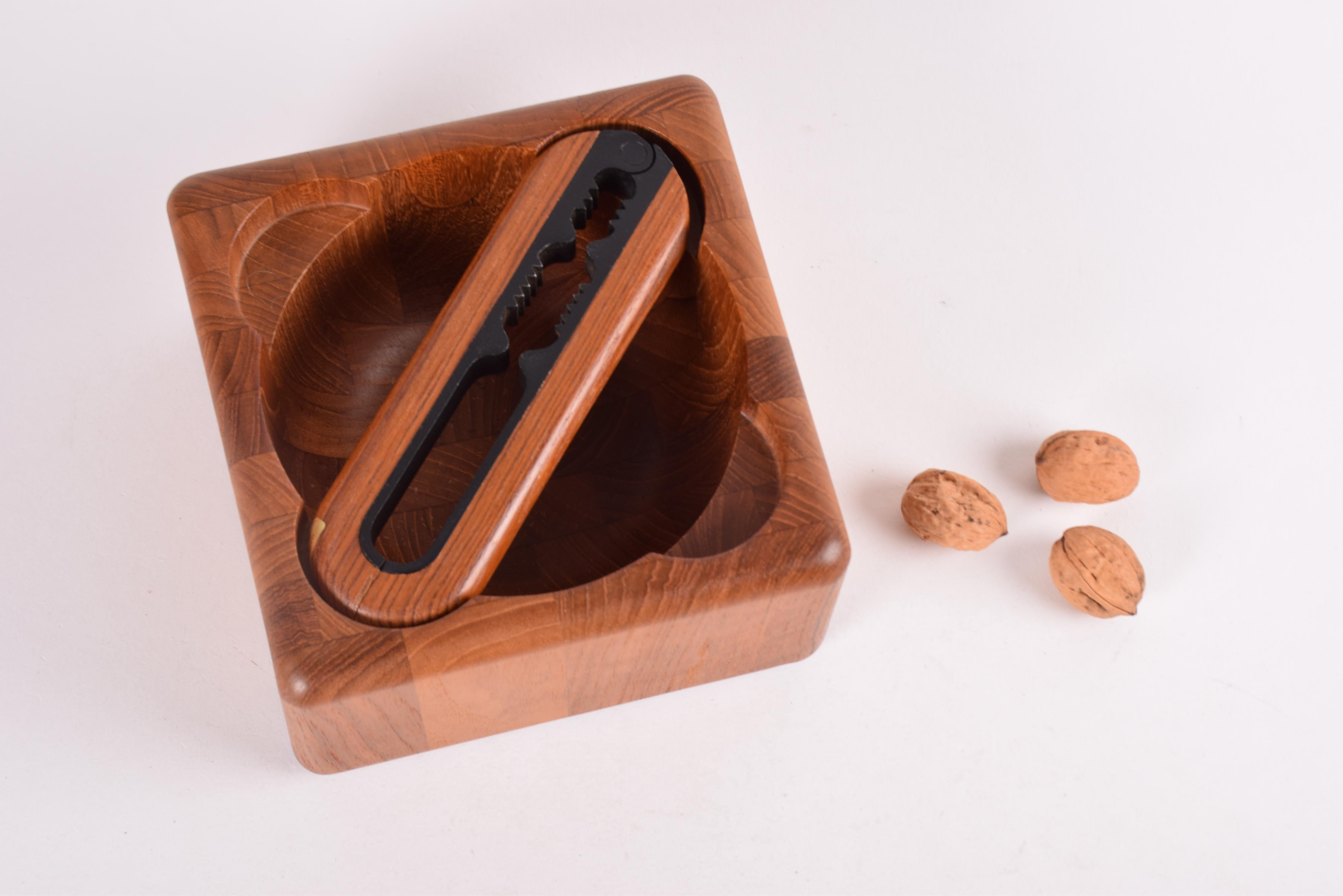 Midcentury Danish nutcracker and bowl made of solid staved teak. Designed by Flemming Digsmed for Danish wood manufacturer Richard Nissen, Langaa. The nutcracker is made of steel with handles of solid teak. The original box is included. 

The