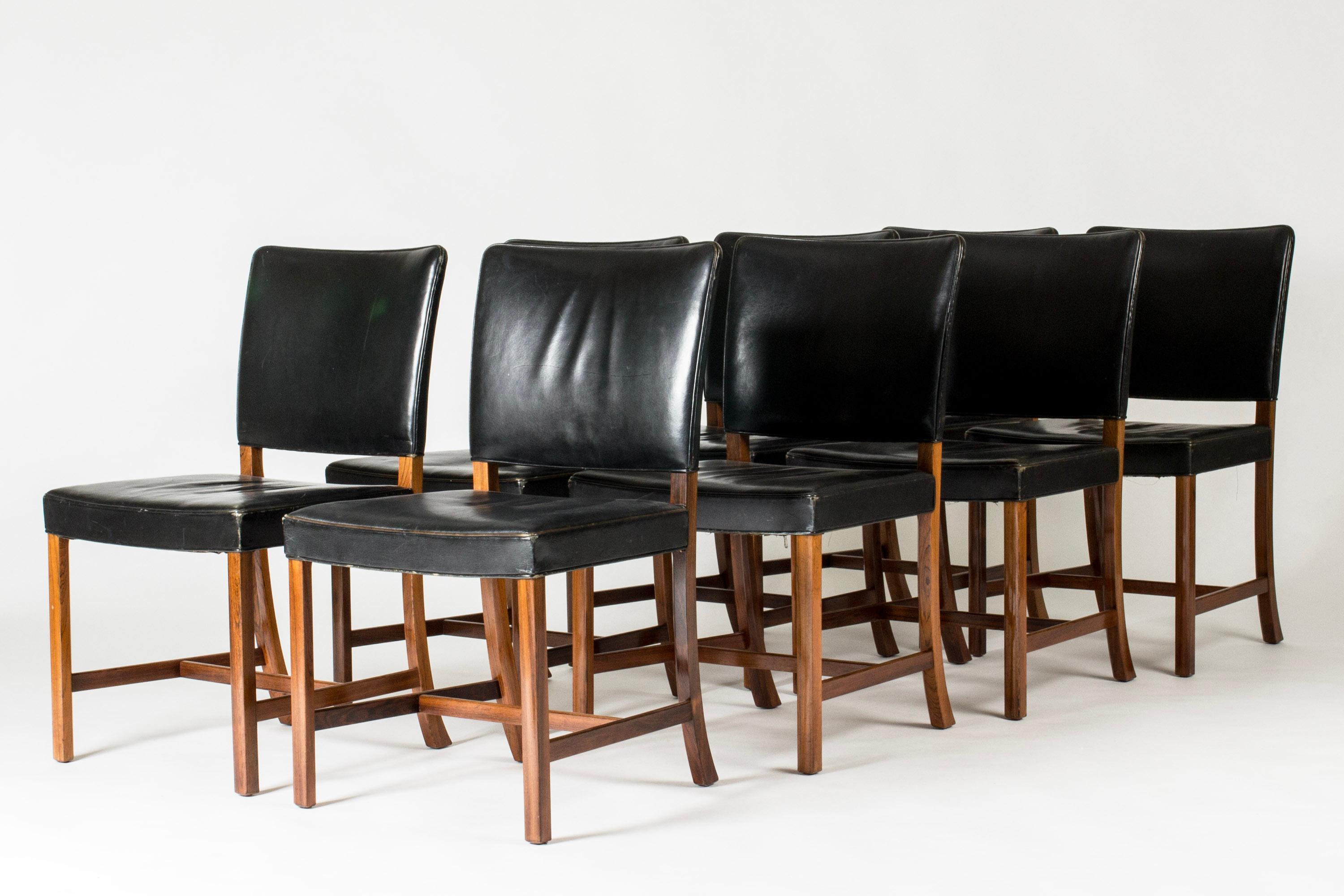 Set di otto eleganti sedie da pranzo di Ole Wanscher, realizzate in legno di palissandro con sedute e schienali in pelle nera. Linee pulite, elevato comfort.