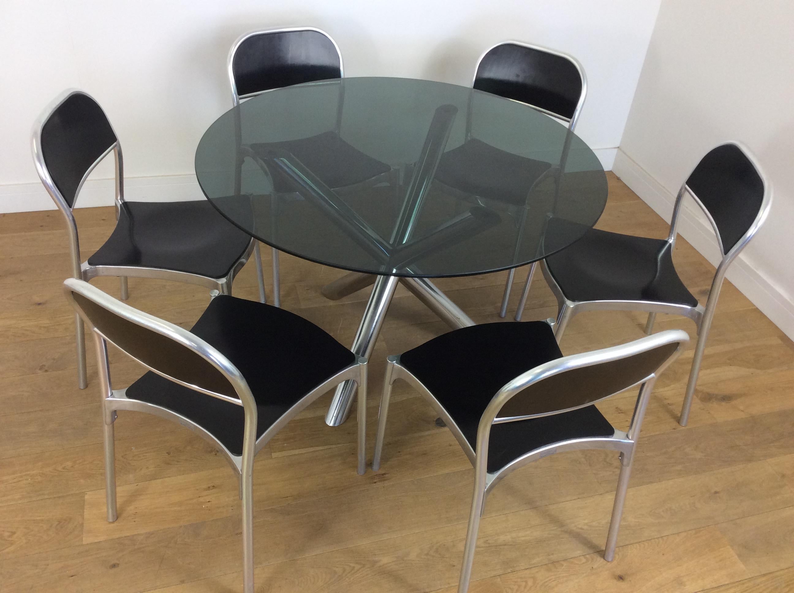 Midcentury chrome table with smoked glass top and six aluminum chairs.
X frame tubular chrome base with thick plate glass top, six aluminium chairs with black painted wood seats and back rest.
the chairs by Metalmobilarredo Sandler