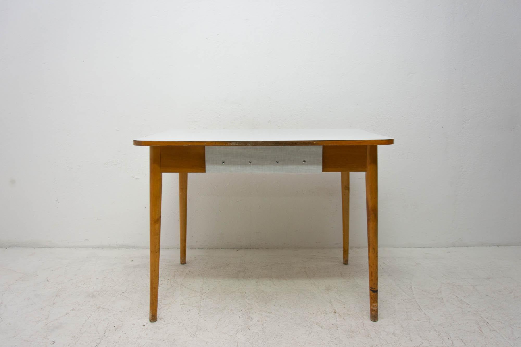 Midcentury kitchen table with a Formica plate, beech legs and one drawer. It was made in the former Czechoslovakia in the 1960s. In good vintage condition, the legs bear signs of age and using in the form of a few scratches.