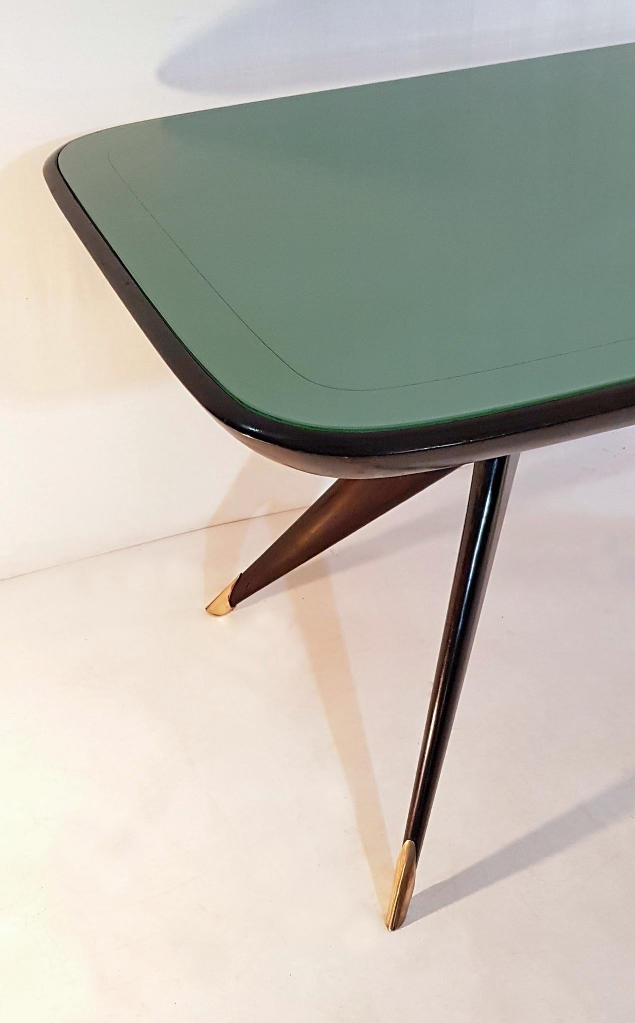 Fabulous dining table produced in Italy in the 1950s. The base is made from stained beech and the legs has brass caps and finally the top is made from glass which has a green/turqoise vivid color. Easily sits eight people. In excellent condition.