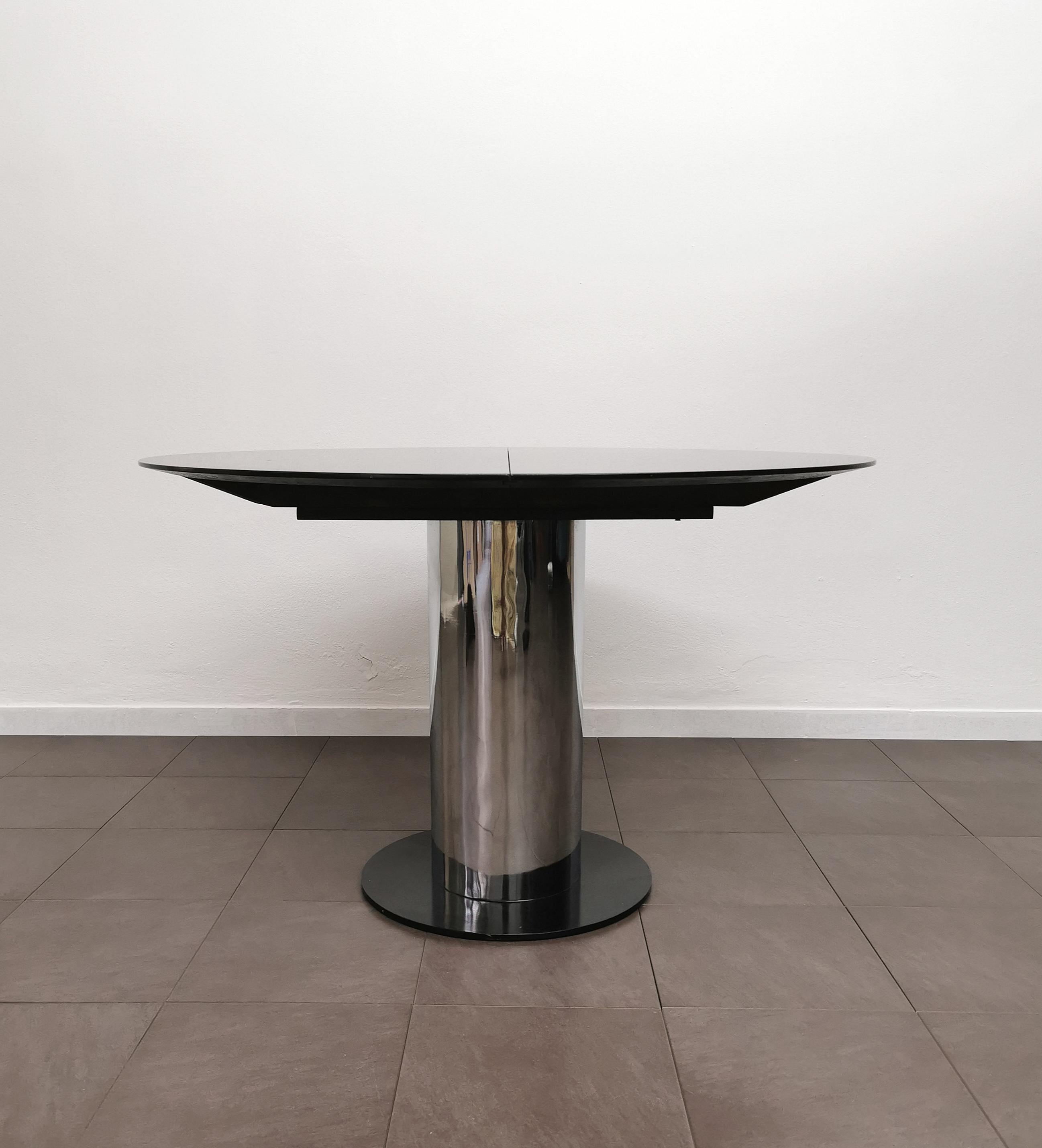 Dining table made in Italy in the 70'. The round-shaped table was made with a black enamelled wooden top with an extendable mechanism. Central support in chromed metal with circular black enamelled metal base.
I also want to emphasize the fine and