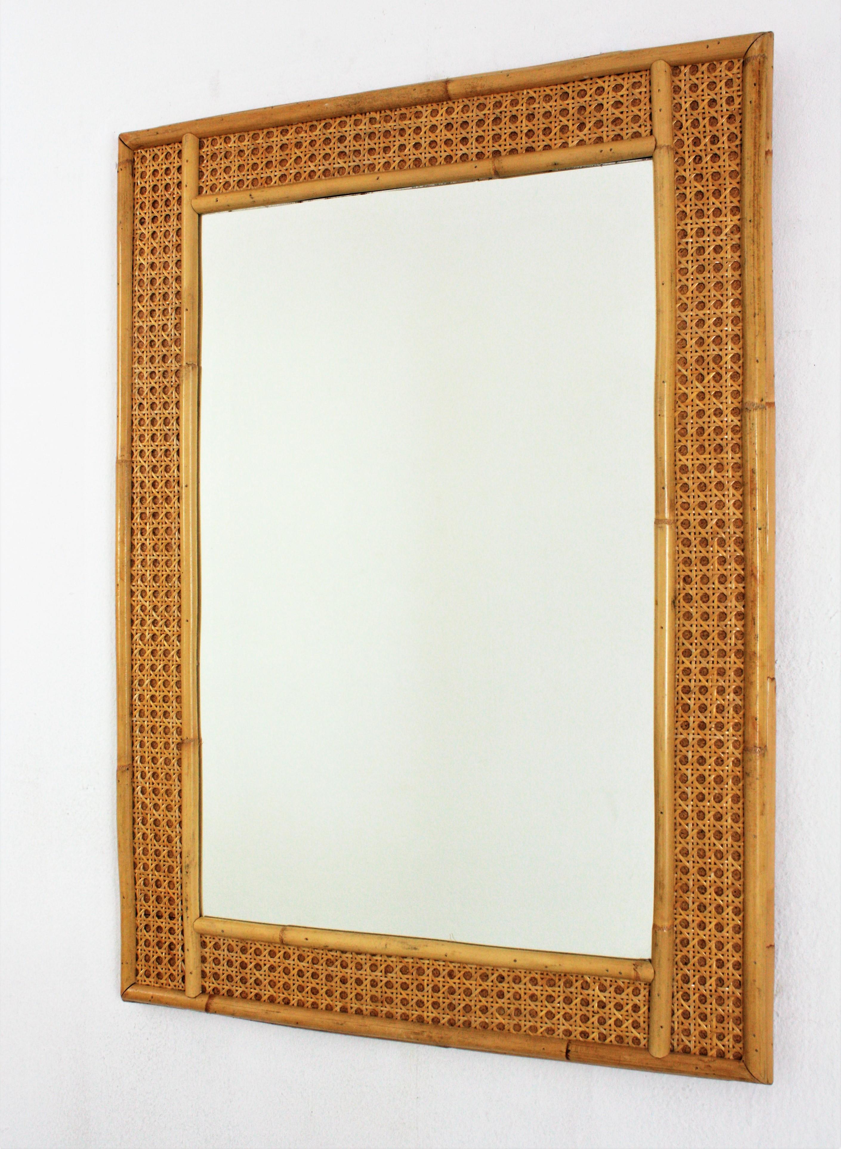 Eleganter Mid-Century Modern Spiegel aus Korbgeflecht und Bambus im Stil von Christian Dior und Gabriella Crespi.
Dieser rechteckige Spiegel aus Rattan, Weide und Bambus stammt aus den 1970er Jahren. Die Struktur aus Bambus mit geflochtener Mitte