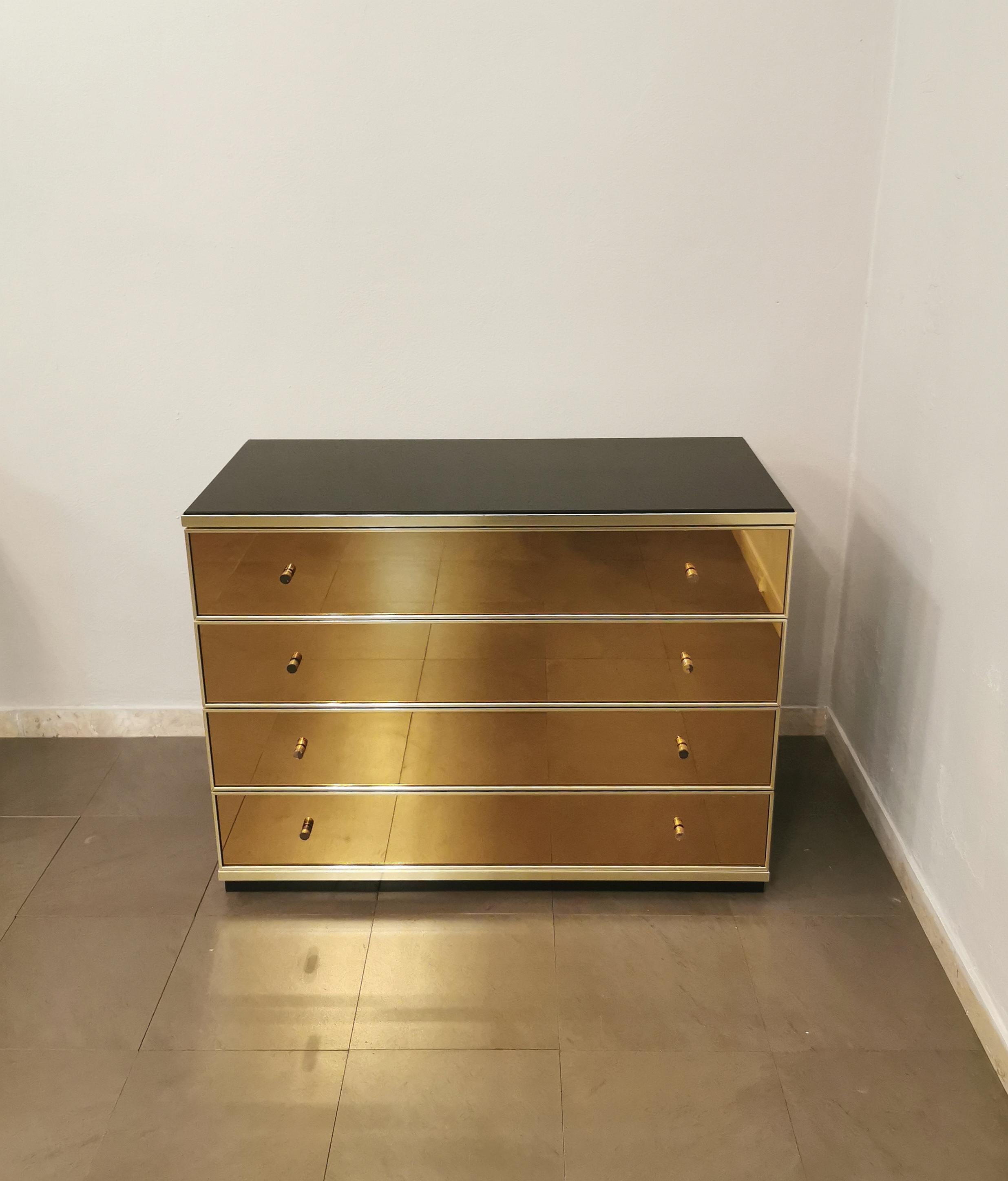 Elegant chest of drawers designed by the Italian designer Renato Zevi in the 70s. The chest of drawers has a black lacquered wooden structure, a dark glass top and 4 bronzed mirrored glass drawers with sand-colored suede inside. Finishes in gilded