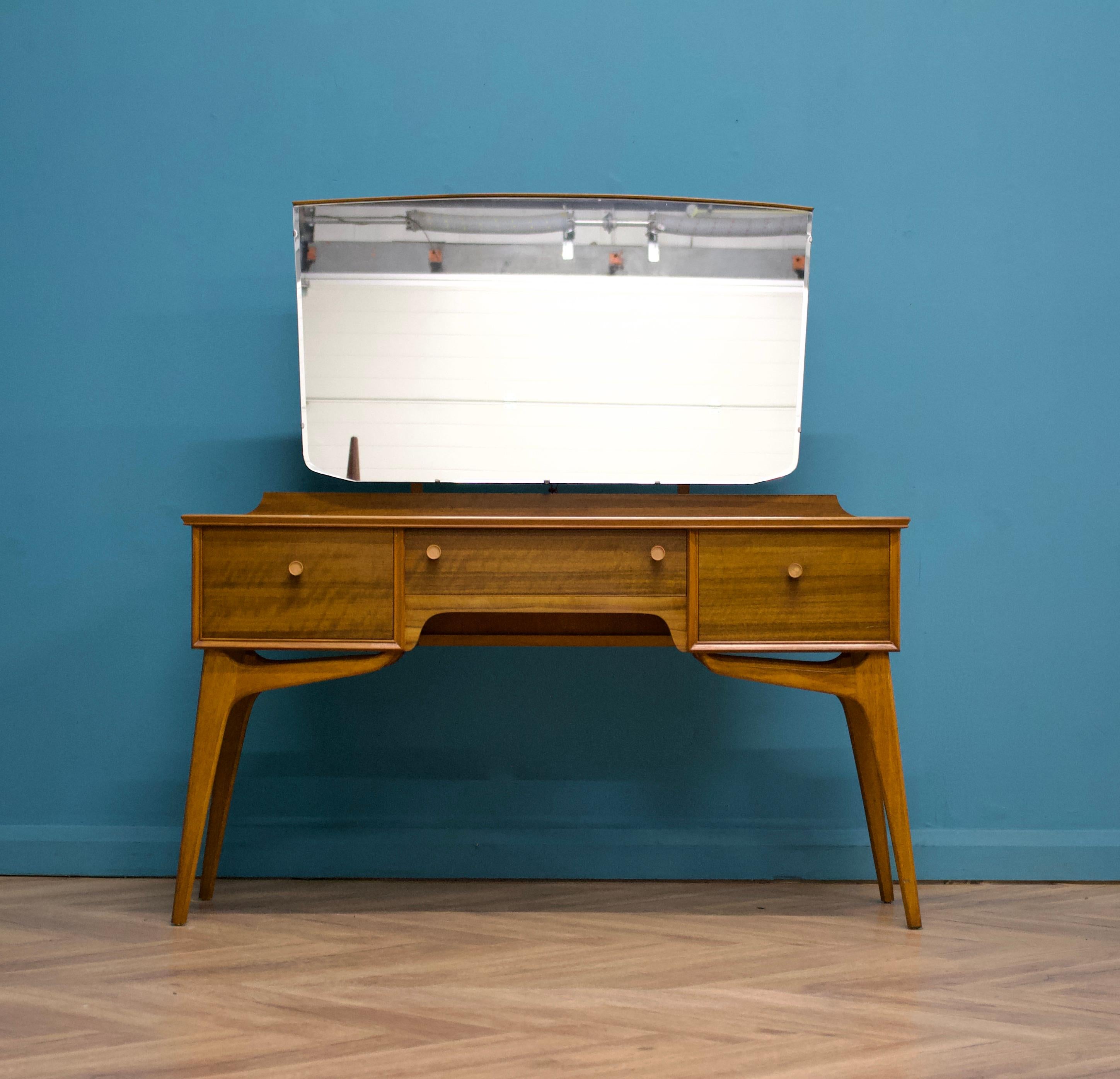 - Mid Century dressing table by Alfred Cox.
- Manufactured in the UK.

- Made from walnut & walnut Veneer.

- Featuring 3 drawers and a large centralised mirror.