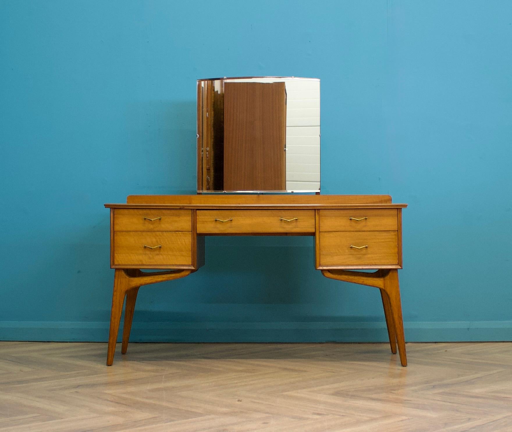 A mid-century walnut dressing table from Alfred Cox, circa 1950s.


The dressing table includes five drawers and a fixed mirror


Height to the top of the mirror is 126 cm 