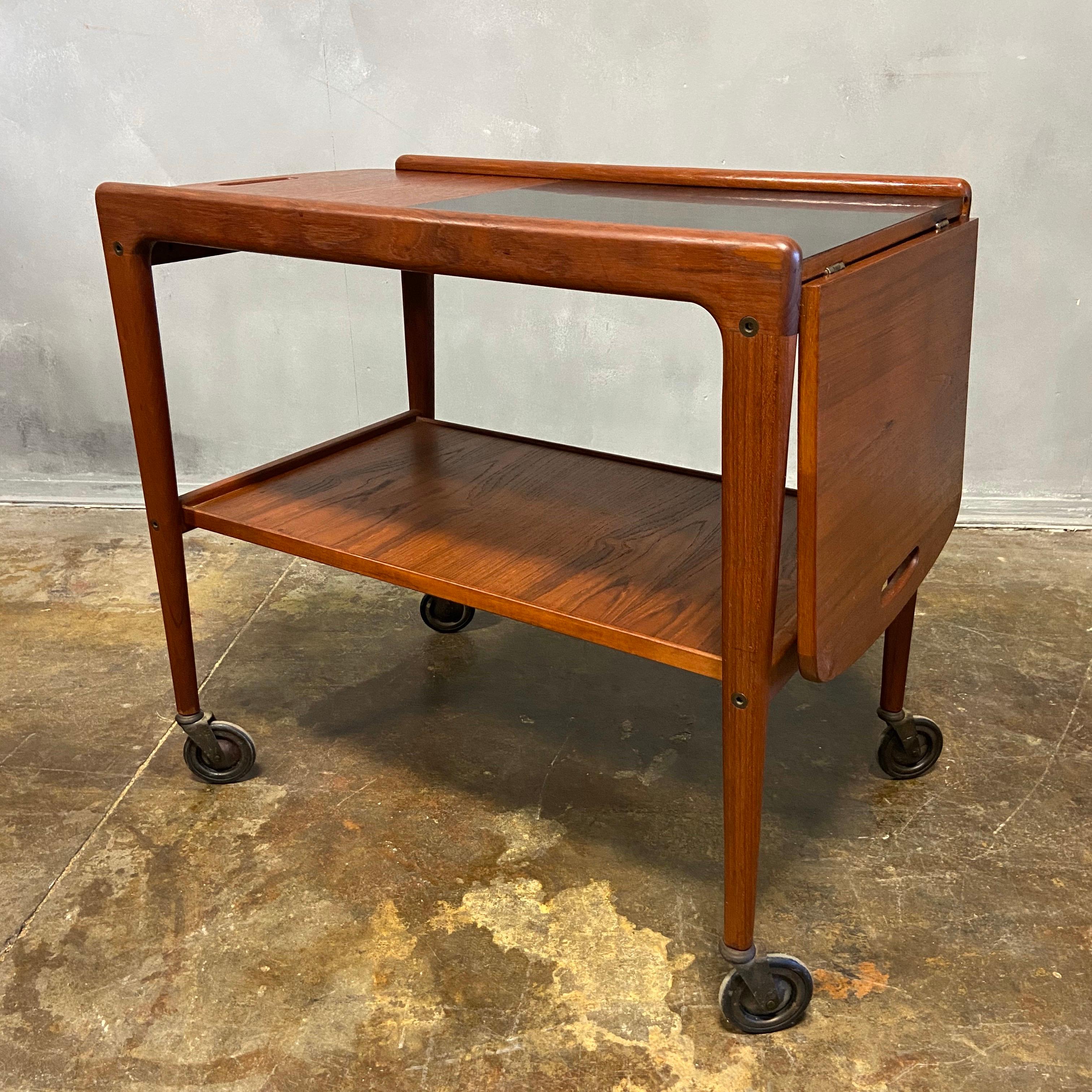 For your consideration is this wonderful Scandinavian Modern bar cart or server with a drop-leaf top by Yngeve Ekstrom. Made of teak wood with sculptural handles on either side. The total height is 25 inches and the height of the shelf is 12 1/2