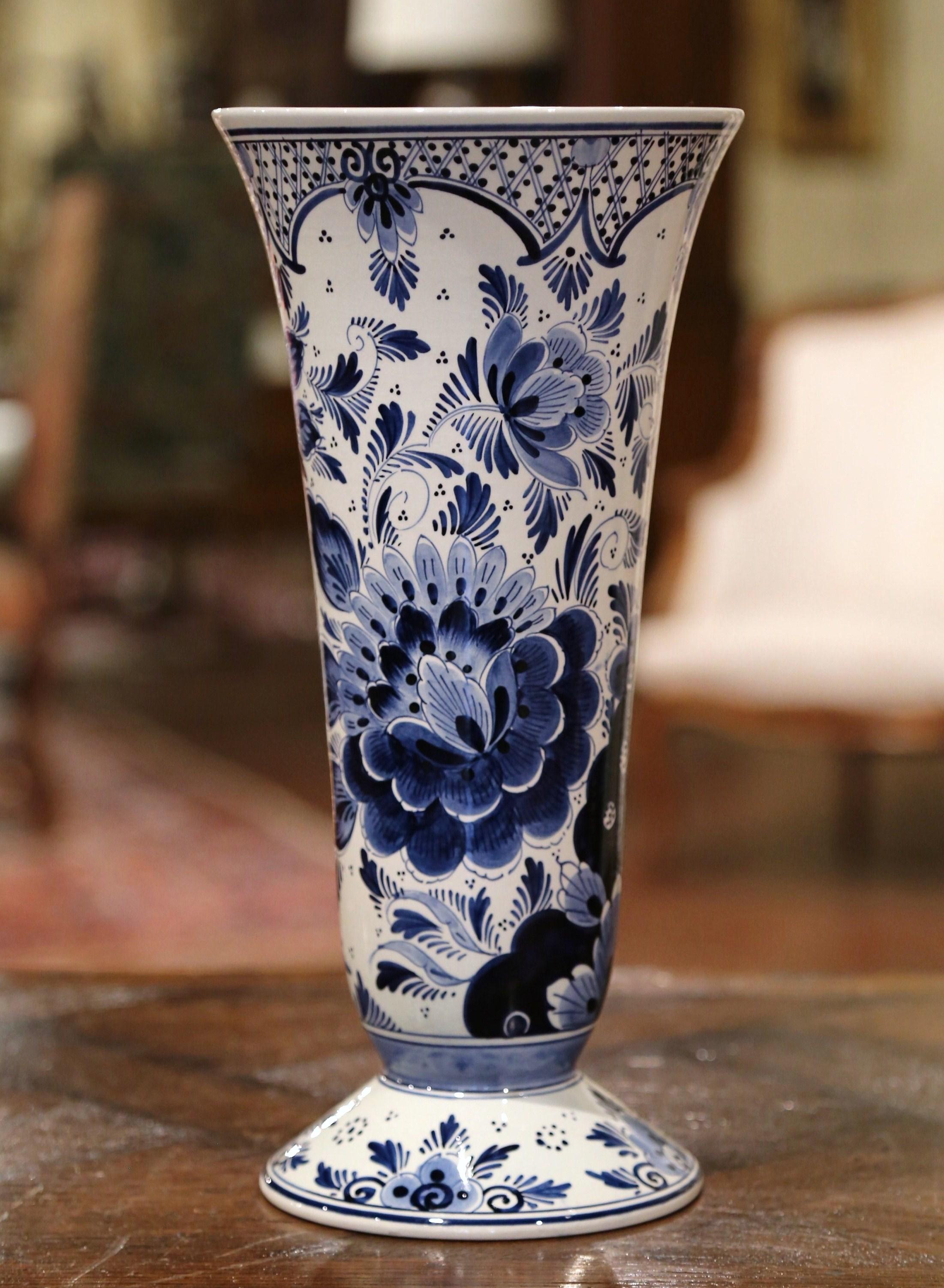 Decorate a mantel (fireplace) or buffet with this tall, ceramic vase from Holland; sculpted circa 1960, the traditional antique vase features a tapered form with a long neck and a wide mouth. The ceramic vase is hand painted with bird and floral