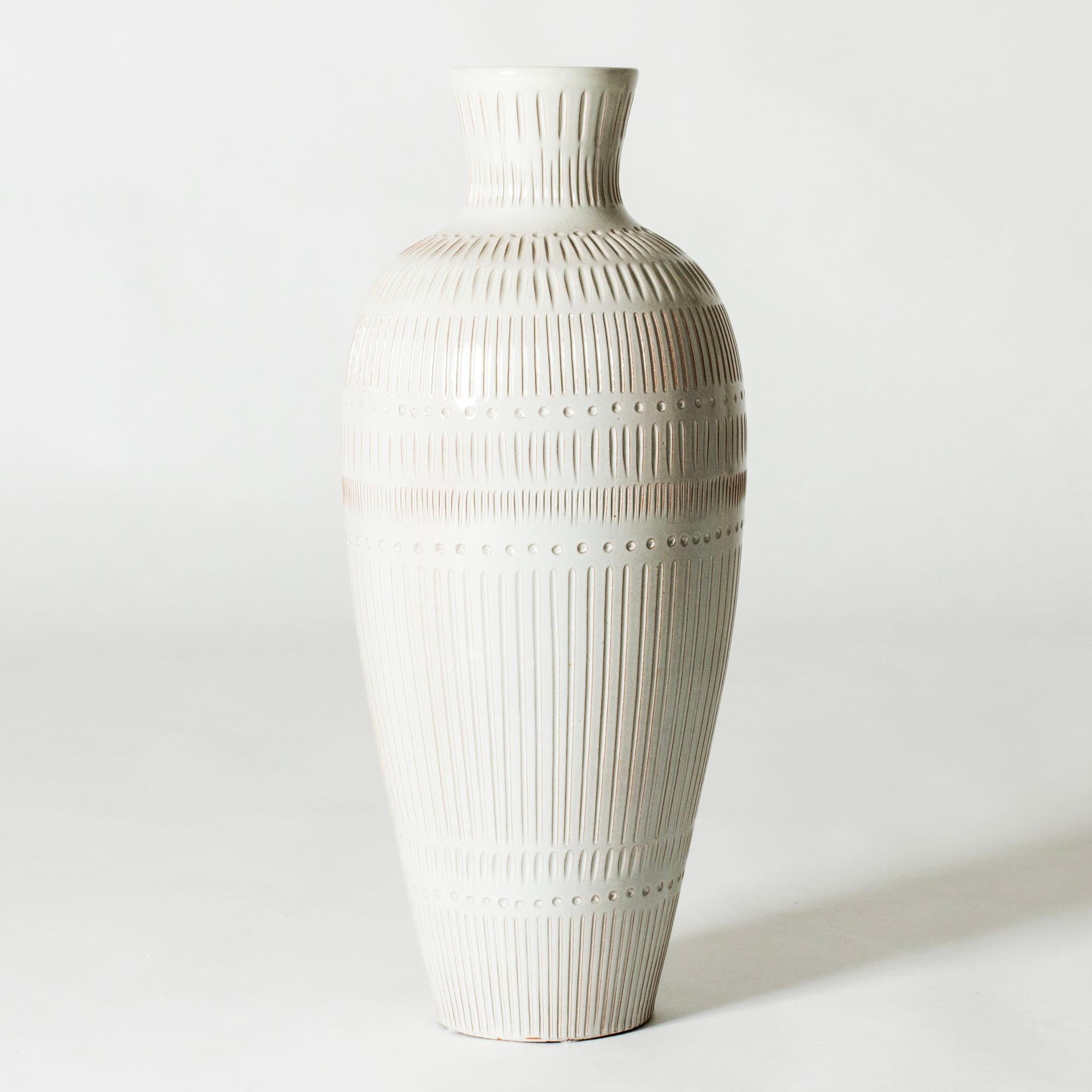 Auffällige Bodenvase aus Steingut von Anna-Lisa Thomson, halbtransparent weiß glasiert. Dekoratives, geprägtes grafisches Muster.

Die Künstlerin Anna-Lisa Thomson ist vor allem für ihre Steinzeug- und Steingutarbeiten für Upsala-Ekeby bekannt, wo