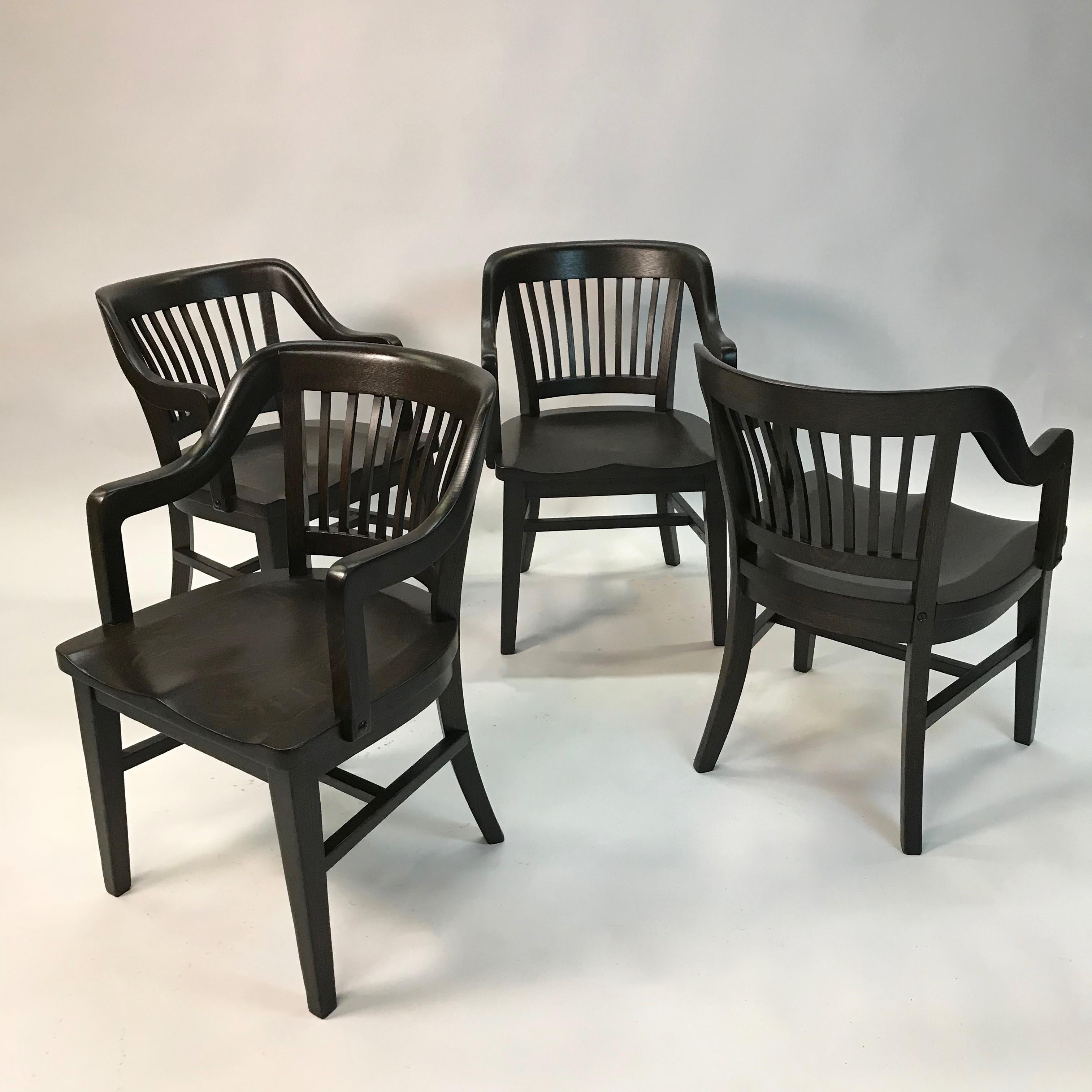 Handsome set of 4, midcentury, ebonized maple, bank of England, courthouse, juror armchairs feature molded seats and an arm height of 27 inches. The chairs are interesting as they sport a more boxy frame than the typical bank chair.