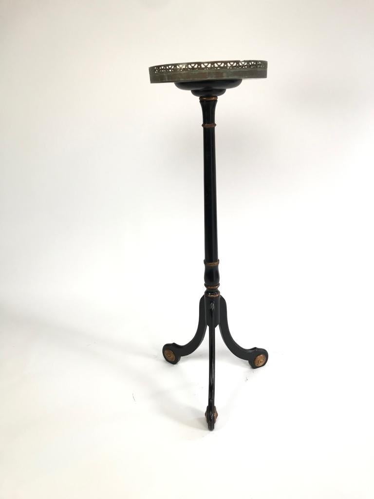 A lovely single pedestal in ebonized wood with brass detailing standing on 3 decorated feet with scroll details.
