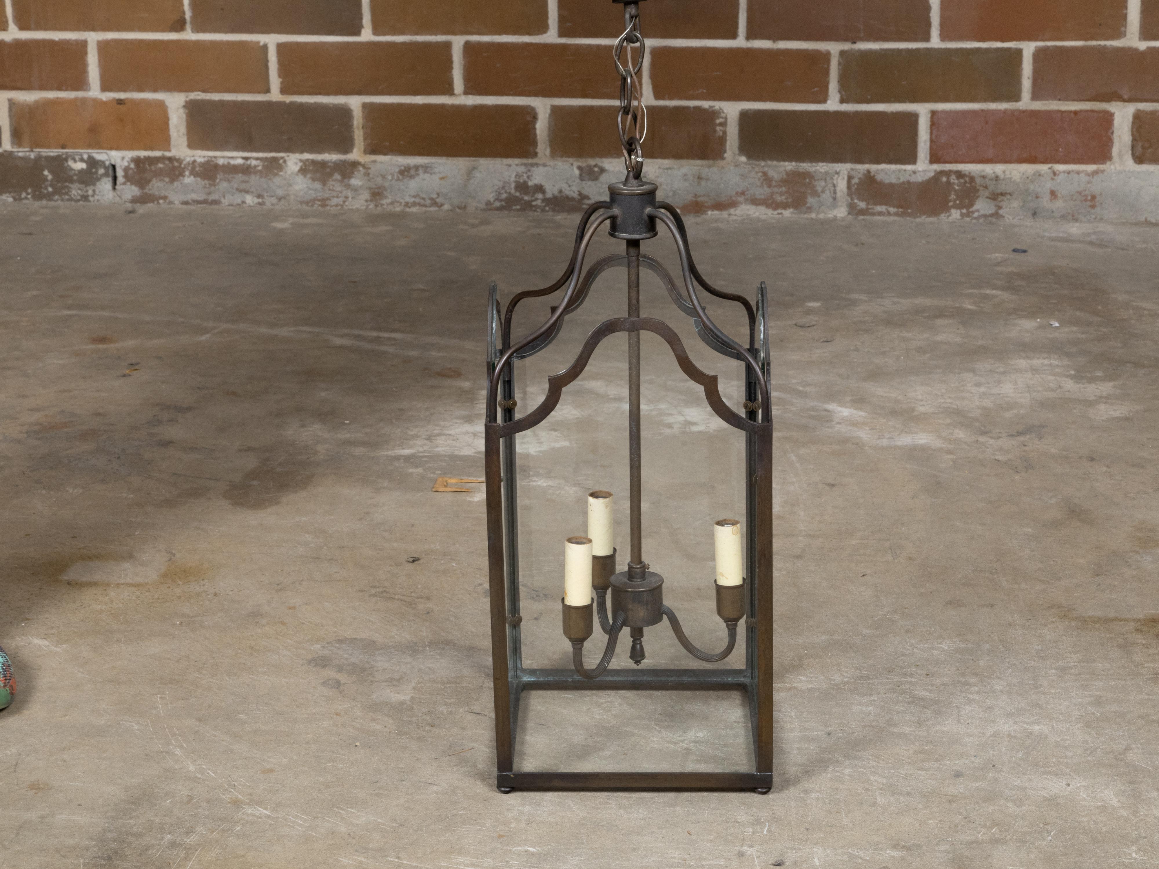 Farol de bronce inglés de mediados de siglo, con tres luces y paneles de cristal. Nacida en Inglaterra durante el periodo de mediados de siglo, esta exquisita linterna de bronce presenta tres luces, encerradas por paneles de cristal transparente que