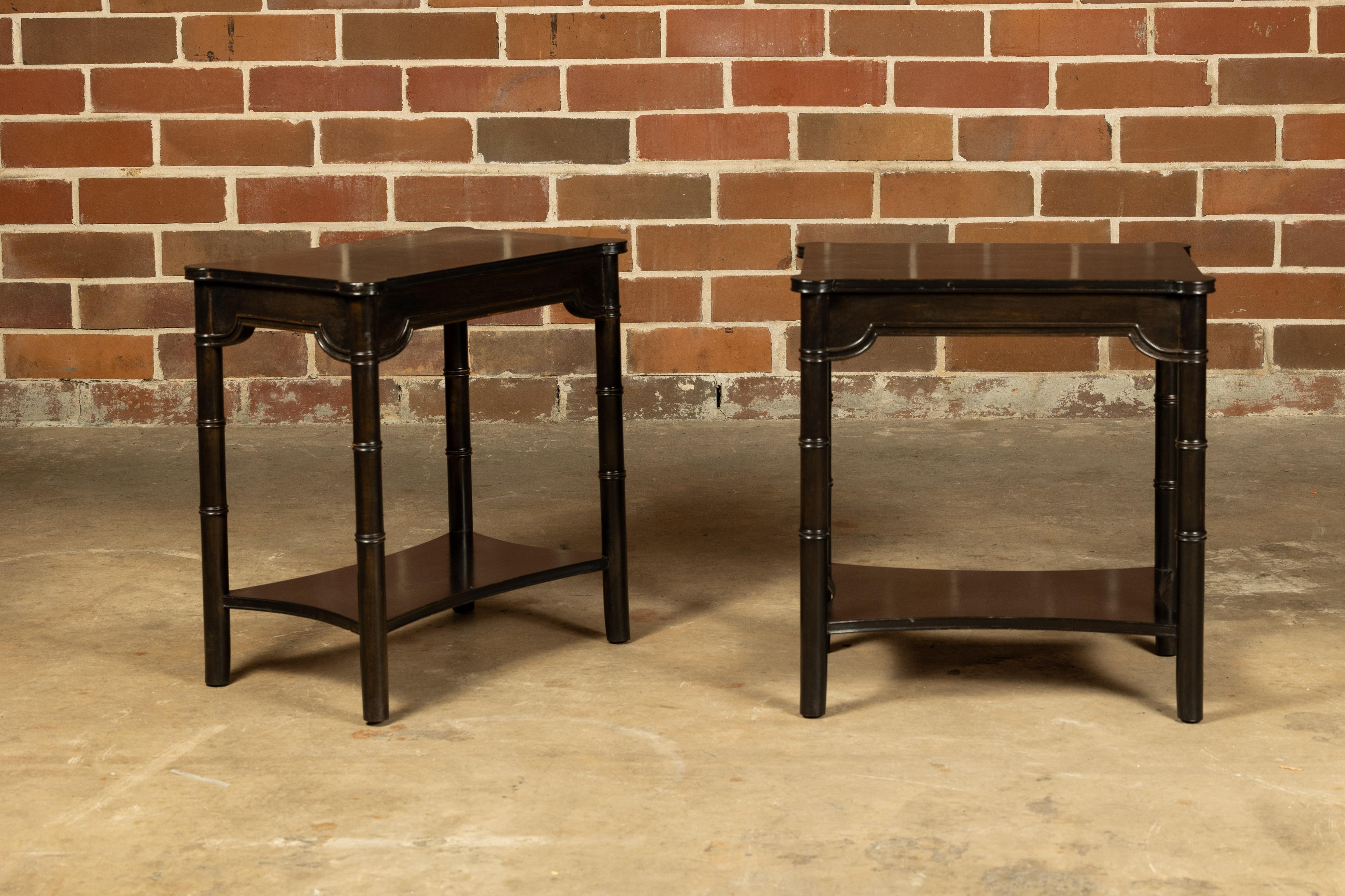 A pair of English ebonized faux bamboo side tables from the mid 20th century with simply carved aprons and low shelves. Immerse yourself in the timeless elegance of these English ebonized faux bamboo side tables, a charming pair from the mid-20th