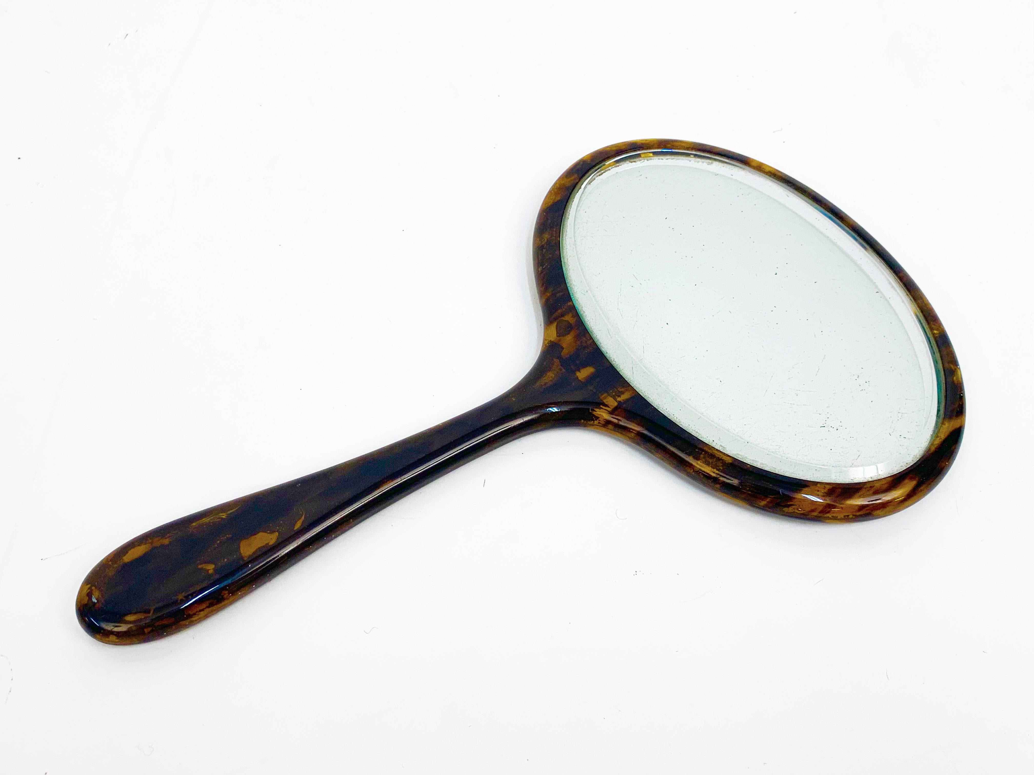 Amazing midcentury oval faux tortoiseshell portable mirror. This item was produced in England during 1950s.

This piece is wonderful because its small dimension will suit bedroom furniture and can be handled on one hand.

This mirror is stylish,