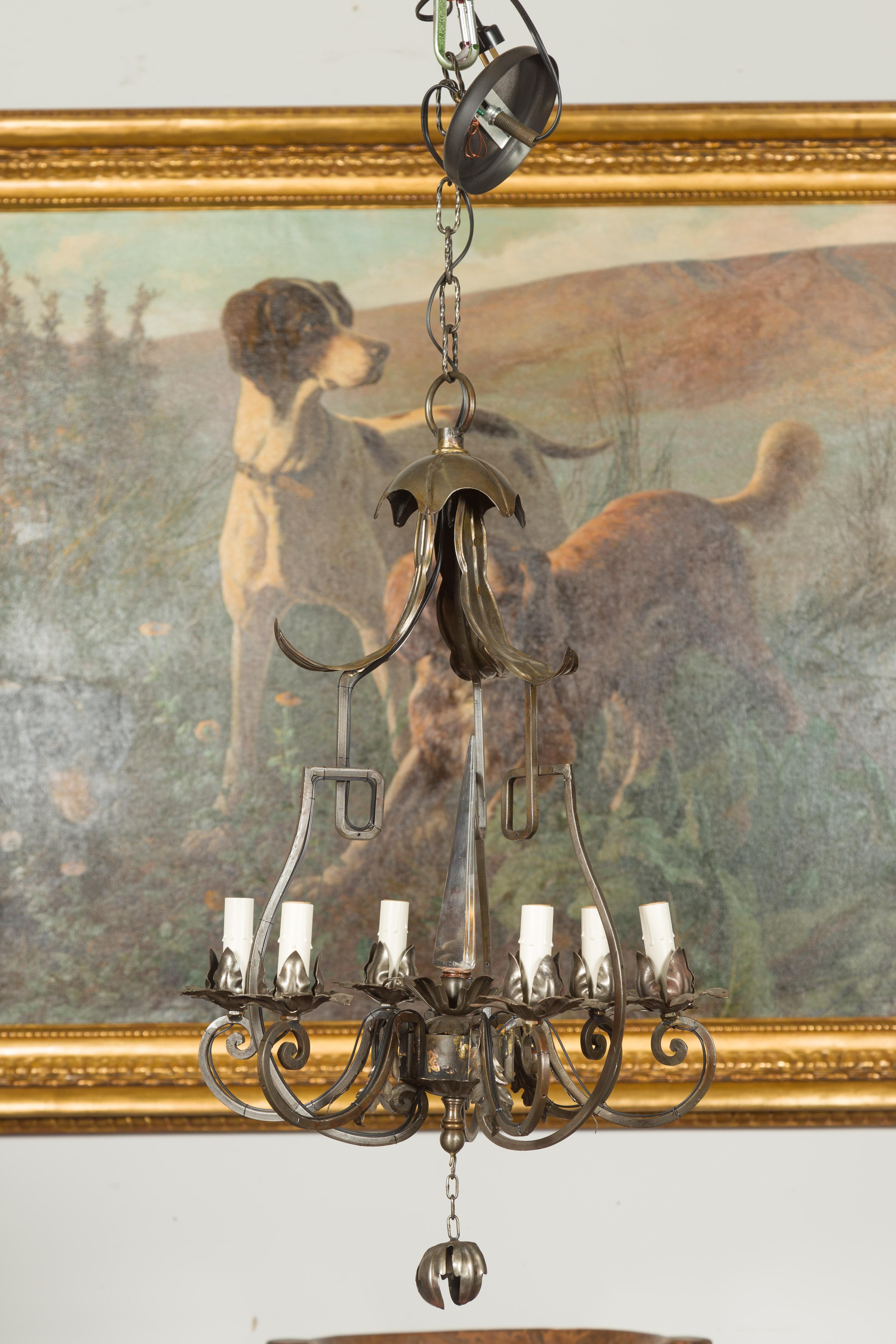 An English vintage polished steel six-light chandelier from the mid-20th century, with scrolling arms and crystal obelisk. Created in England during the midcentury period, this six-light chandelier features a polished steel structure topped with a