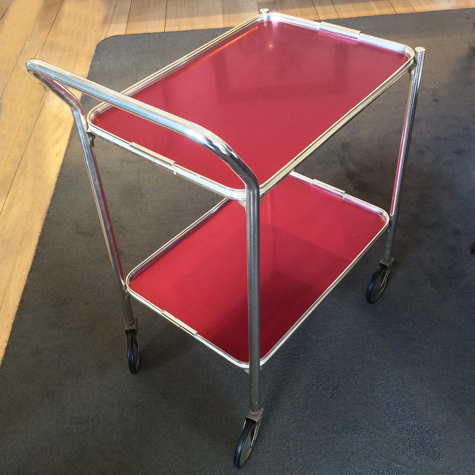 Midcentury polished aluminium bar cart / trolley in anodised red trays, with gold edge surrounds and supports; original black rubber tyred wheels which work as new. The tyres are unworn and do not have any “flat” edges. Soft aged patina but the