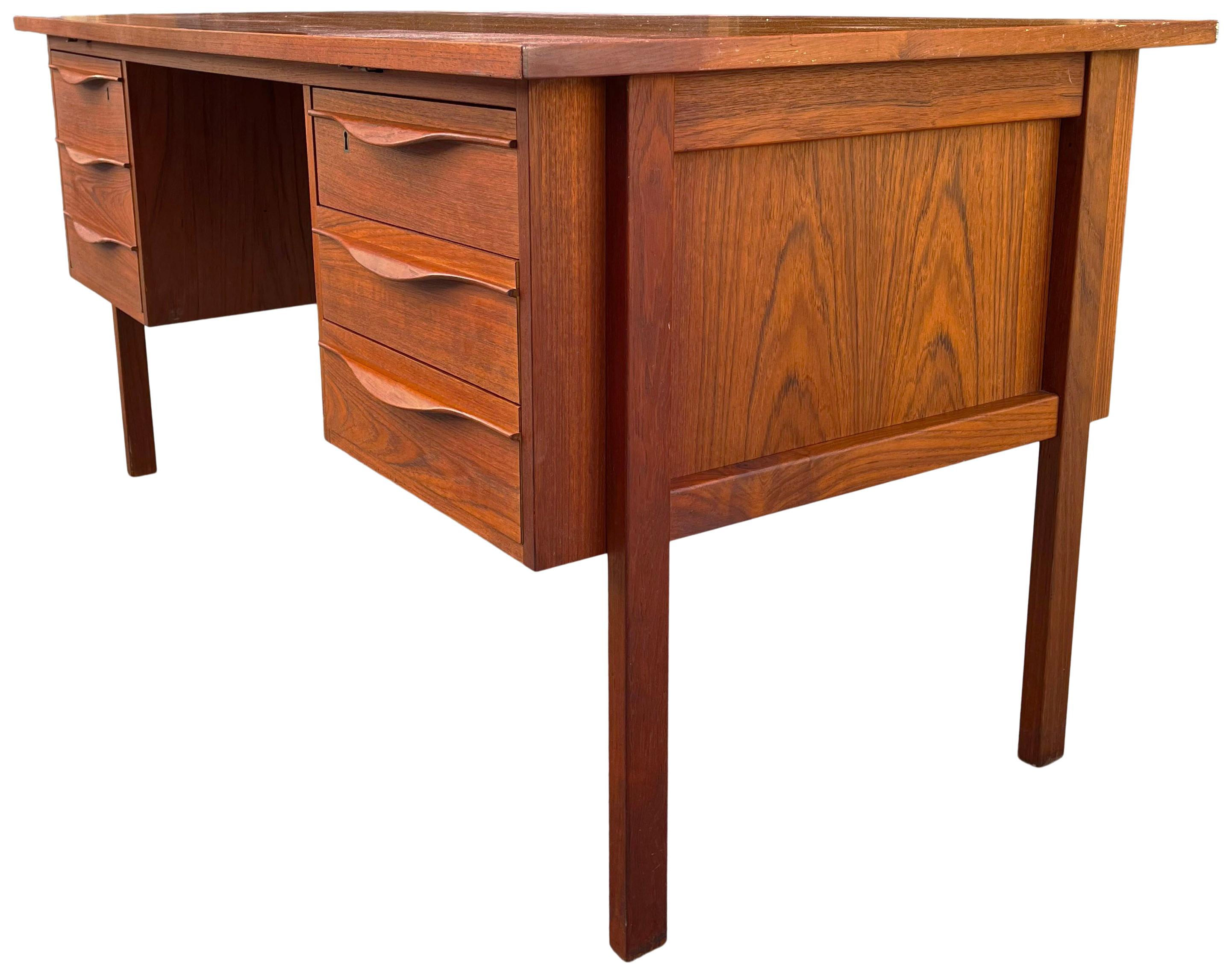Beautiful teak desk with quality construction. Featuring a sliding top the reveals hidden compartment to store files and even liquor bottles. Graceful curved pulls. In original condition showing very little use for its age. Teak has been oiled and