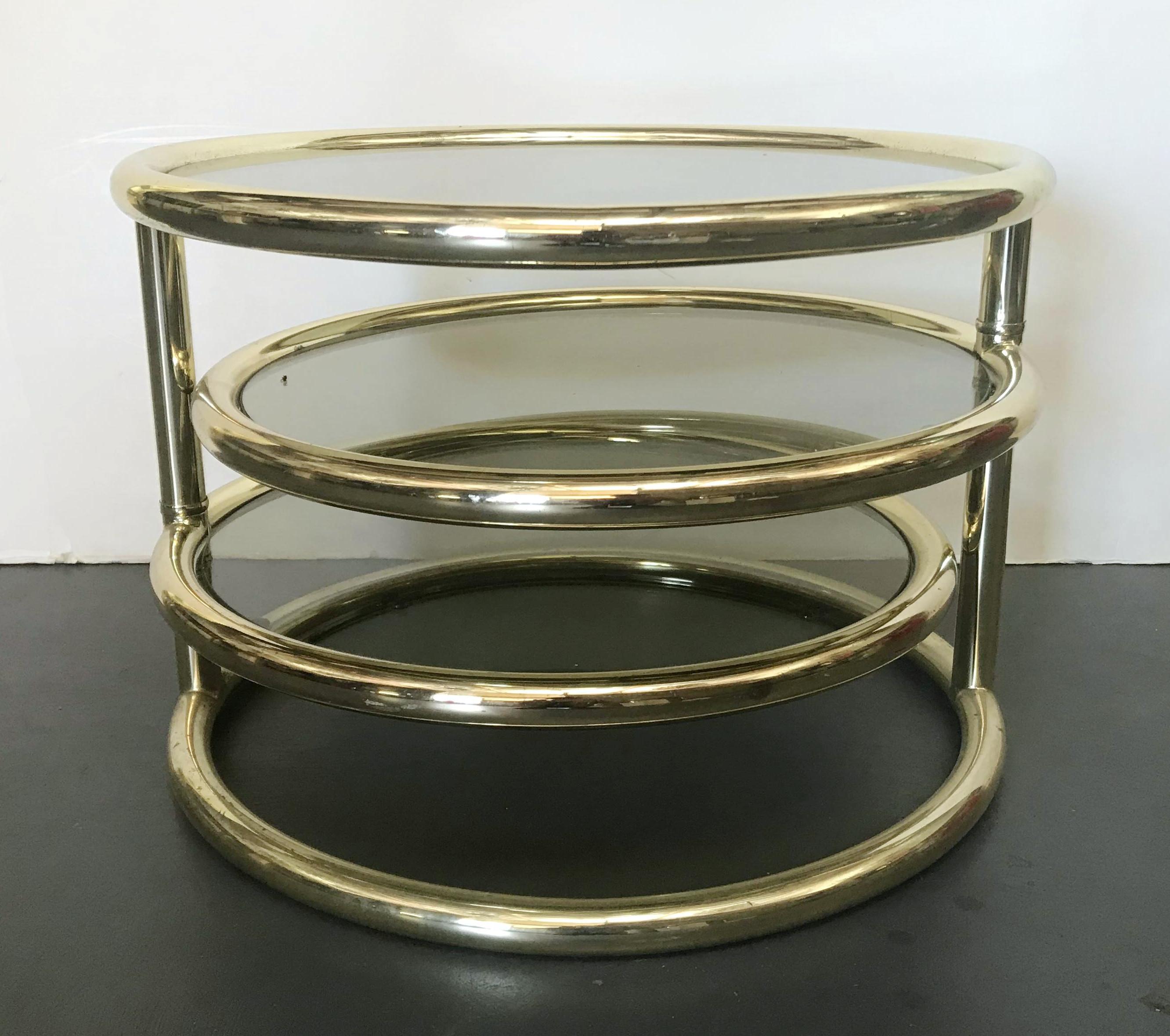 Vintage swiveling round coffee table with 3 tiers of smoky glass shelves on brass-plated metal frame / Made in Italy, circa 1970s
Original 