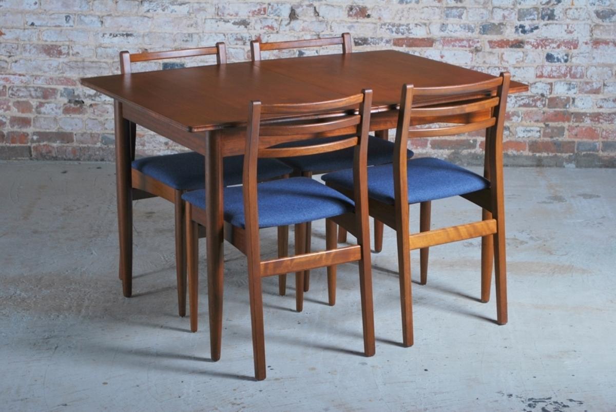A midcentury teak extendable dining table and set of six chairs newly upholstered seats in blue fabric.