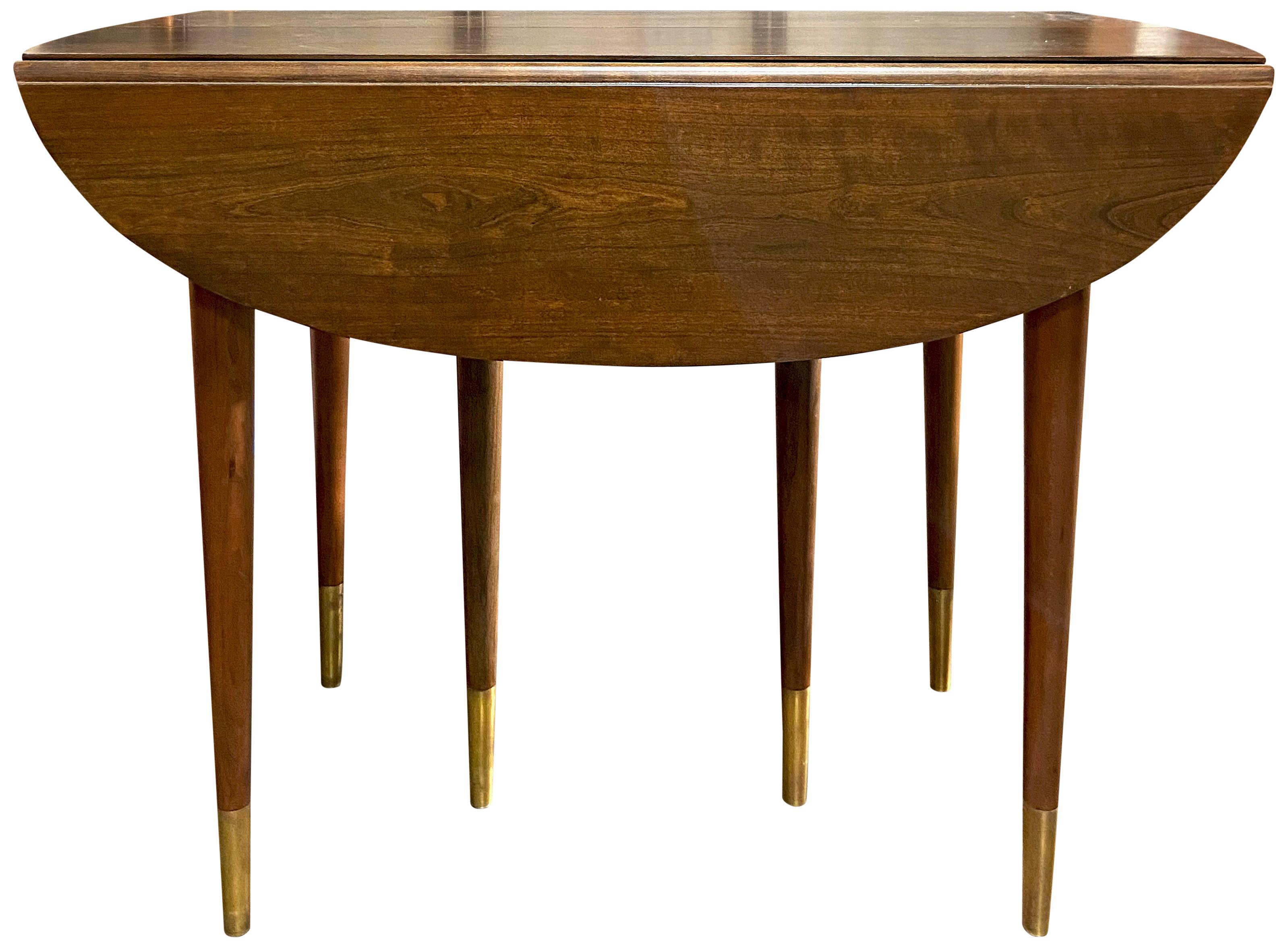 For your consideration is the spectacular dining table by John Widdicomb. Featuring a drop-leaf on either side that opens to reveal an oval shaped table. This table also offers four leaves that are 13 inches wide. The table will fully extend to an