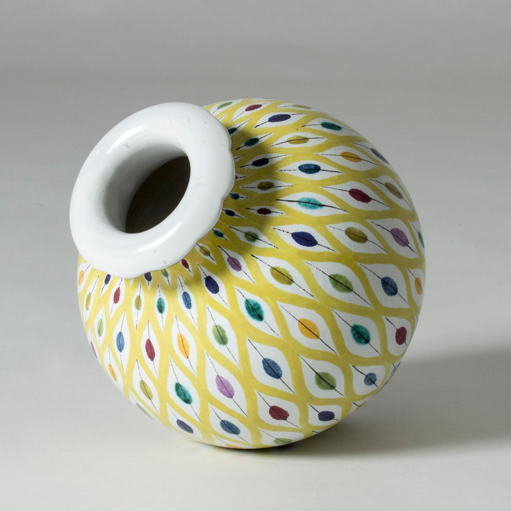 Stunning faience vase by Stig Lindberg in a lovely bulging shape. Beautiful colorful, graphic decor of leaves and vibrant yellow lines.