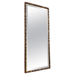 Miroir mural en bois sculpté et doré de style bambou. Verre biseauté
